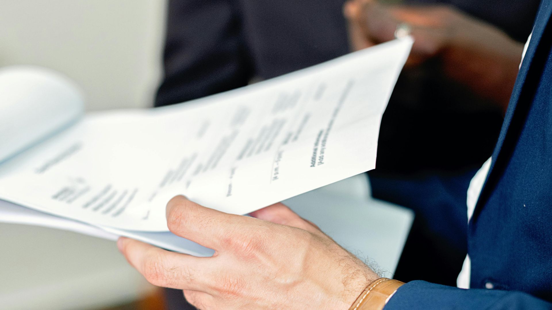 Close-up of professionals reviewing documents in a meeting, focusing on details and teamwork.