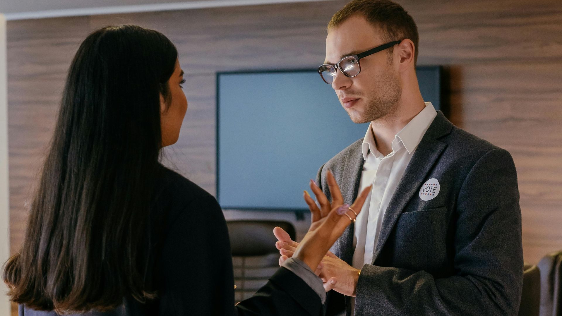 Two professionals engaged in conversation in a modern conference room setting.