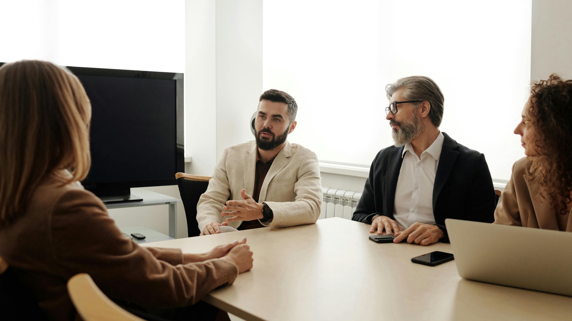 A diverse group of business professionals engaged in a meeting in an office setting.