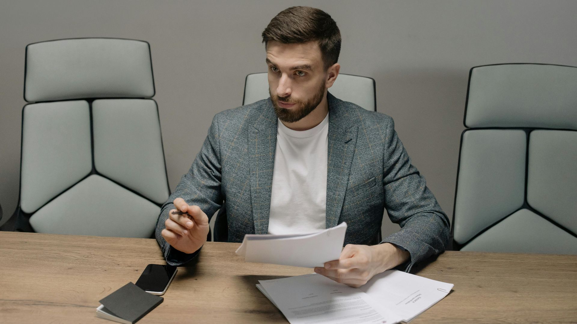 Professional businessman in a suit holding documents during a meeting in an office setting.