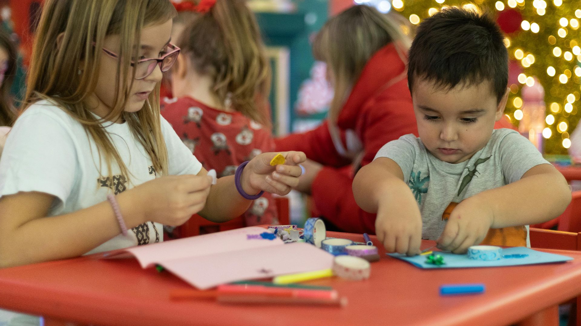 Kids creating festive crafts in a colorful, Christmas-themed classroom setting, focused on holiday creativity.