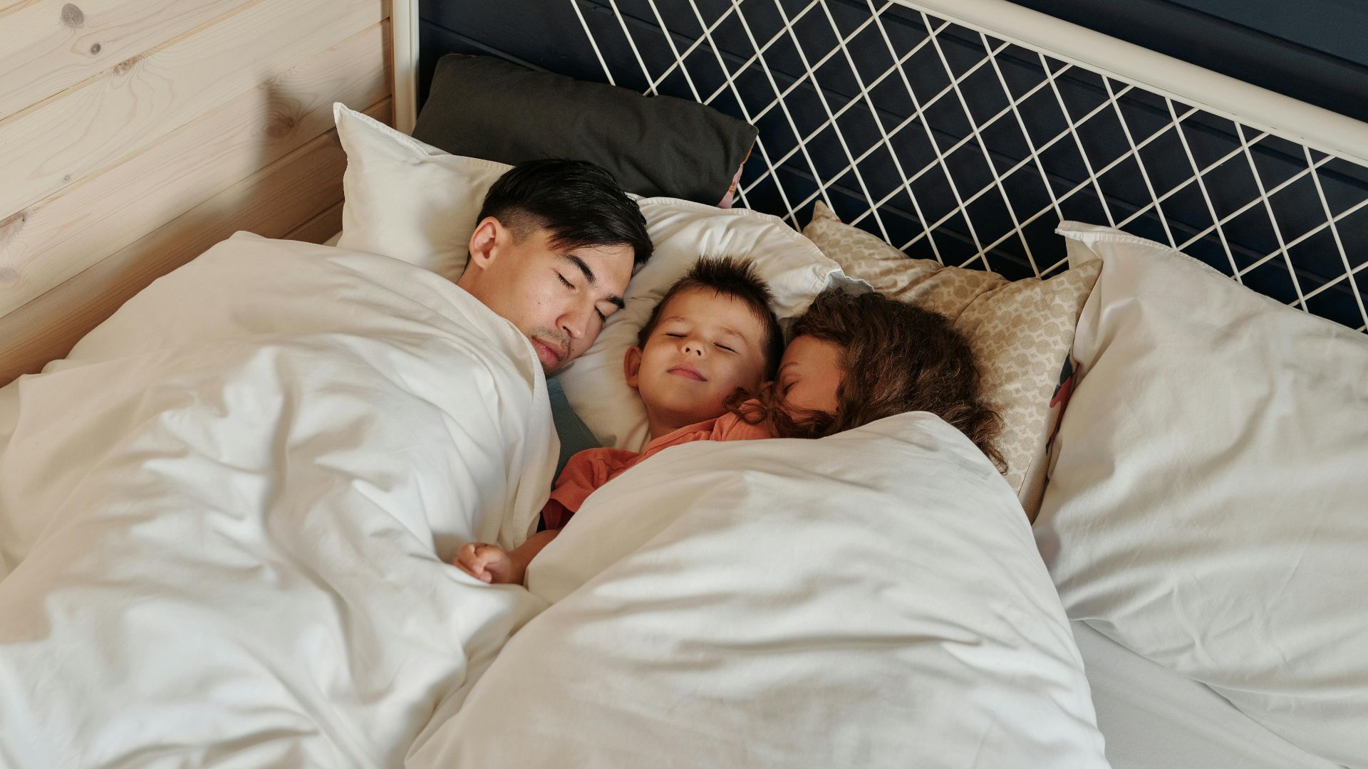A family peacefully sleeping together in a cozy bedroom setting, showcasing warmth and togetherness.