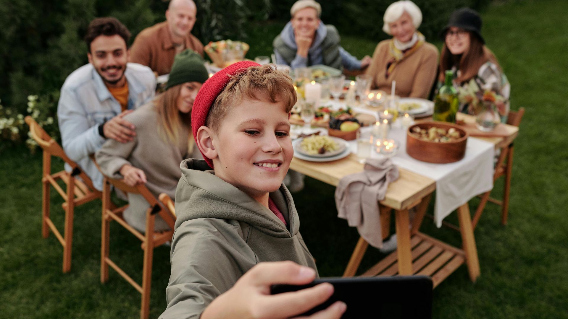Cheerful family taking a selfie during an outdoor garden dinner party.