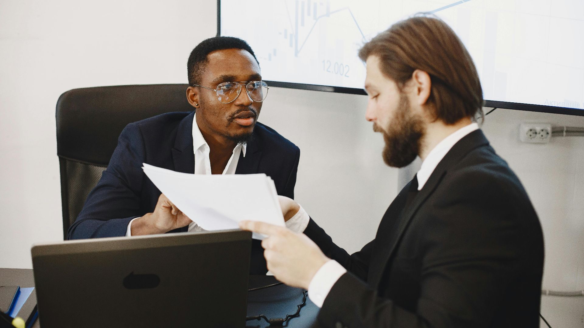 Professionals examining documents in an office business meeting setup.