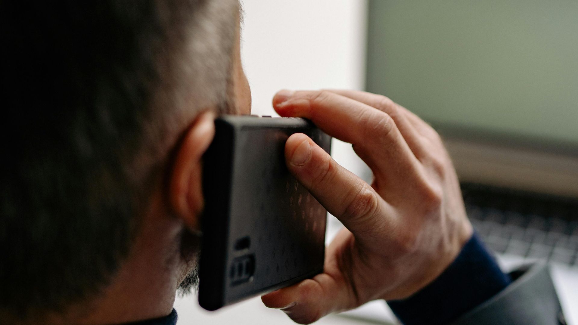 Businessman making a phone call while working on a laptop at the office.