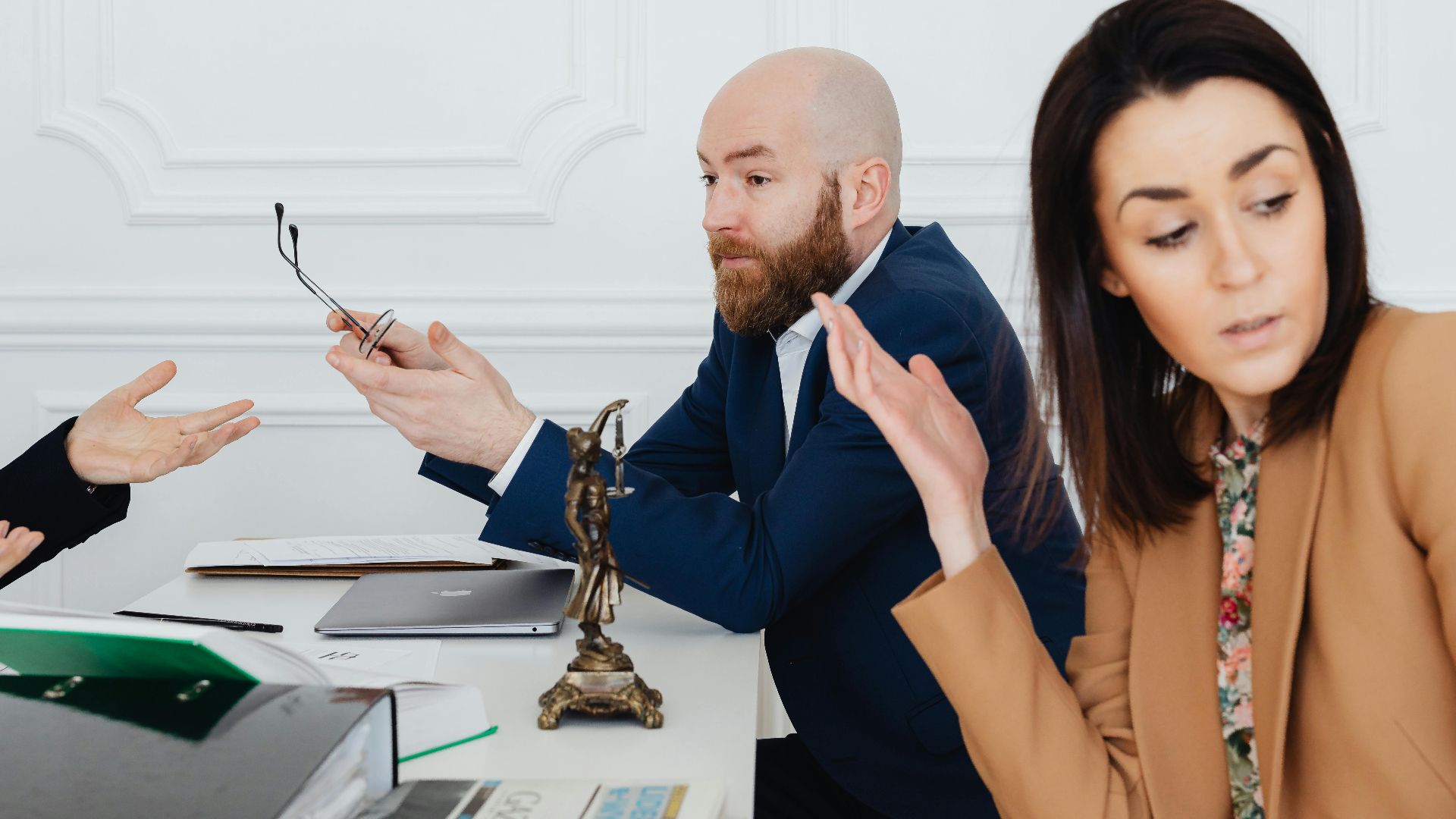 Three adults in a heated discussion with legal documents, indoors.