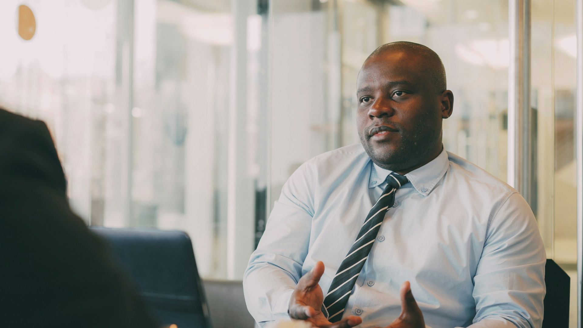 Man in a light blue shirt and tie talking.