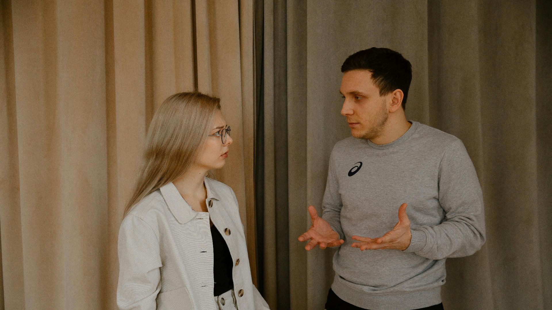 A young couple passionately discussing indoors, capturing intense emotions and gestures.