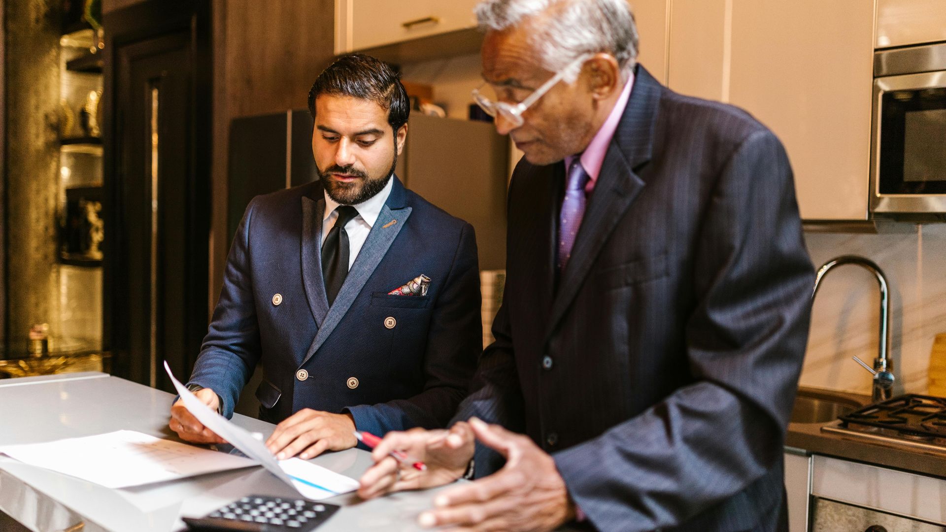 Two businessmen reviewing documents, engaged in a focused discussion indoors.