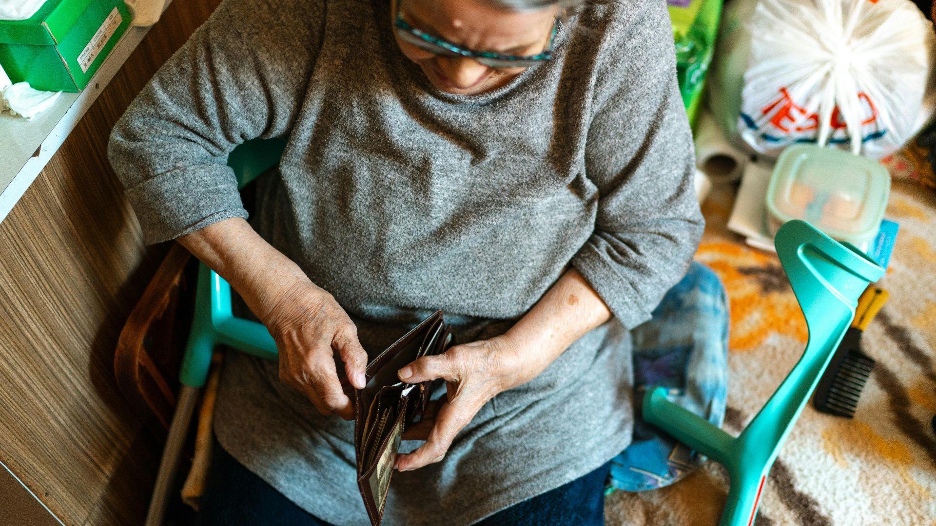 Elderly woman sitting indoors managing her wallet. Home care theme.