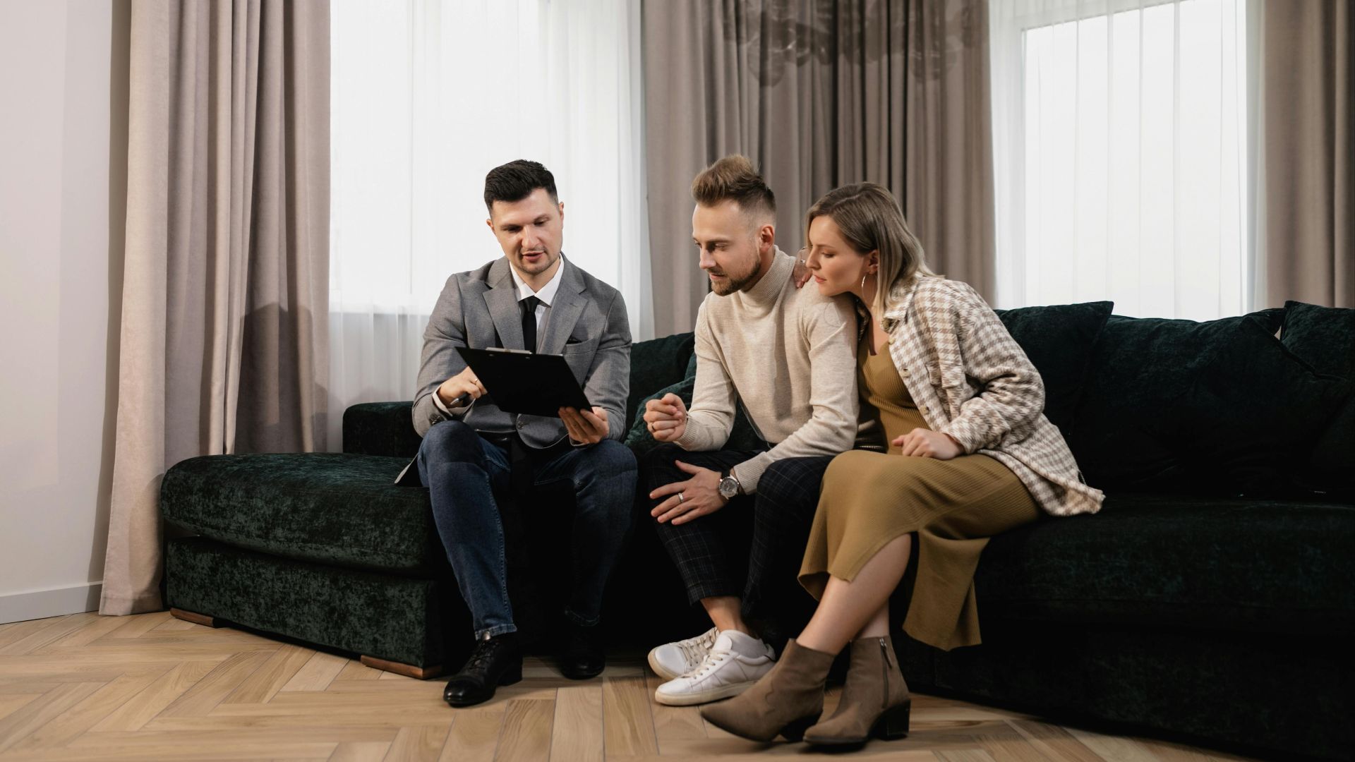 A real estate agent shows a property listing to a couple in a modern living room.