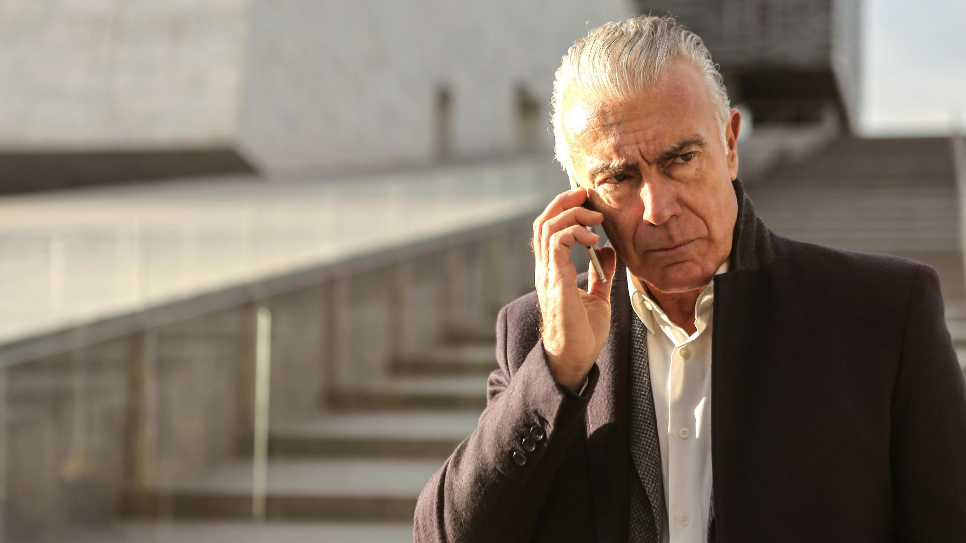 Serious senior businessman using a smartphone outdoors, conveying a professional and pensive mood.