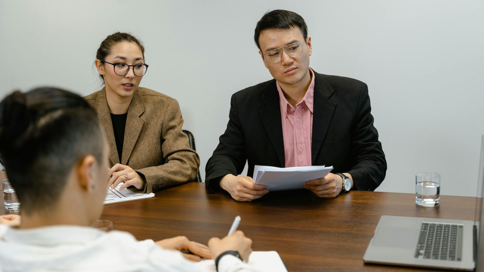 Colleagues engaged in a business meeting, discussing documents in an office setting.