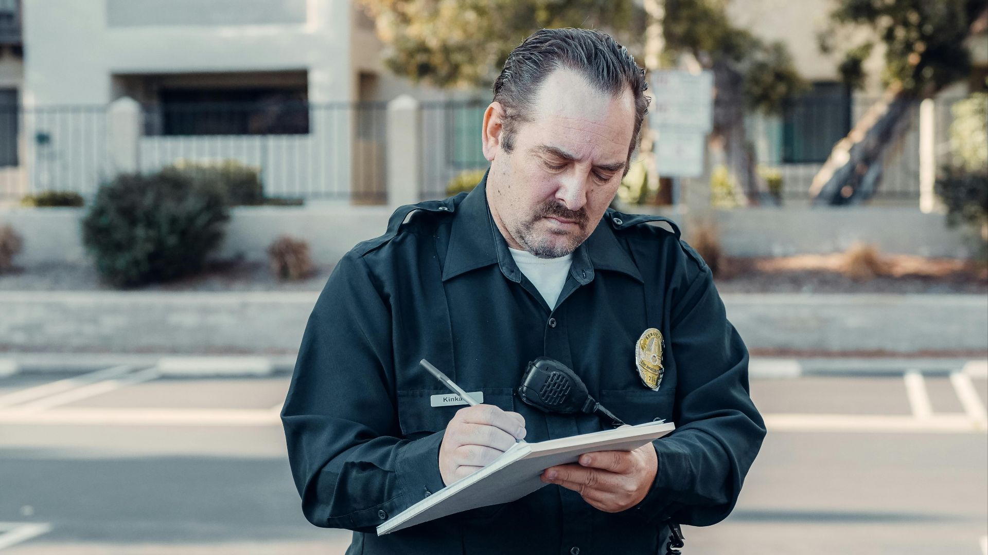 Police officer in uniform writing a ticket on a clipboard outdoors.