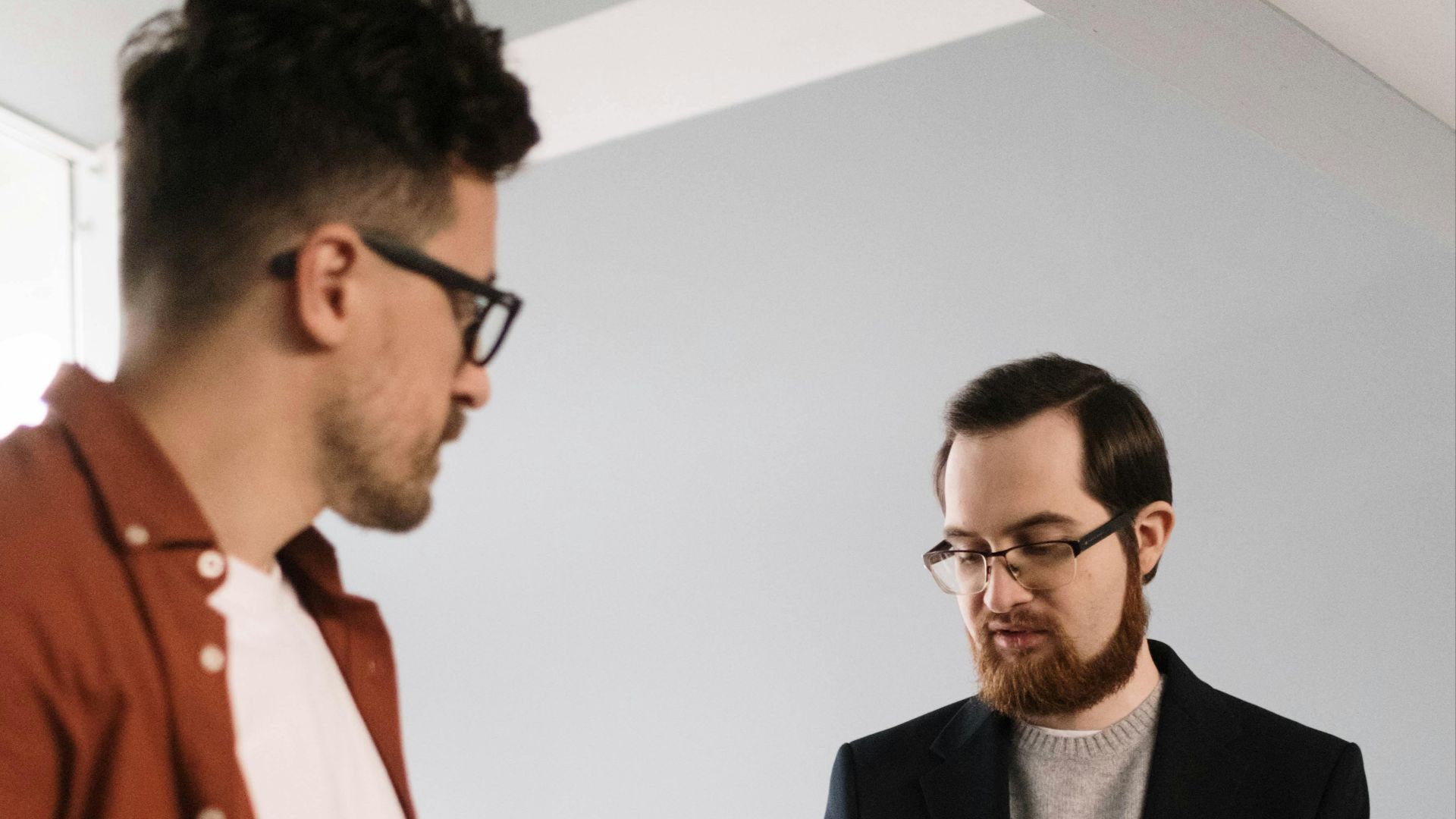 Two men engaged in a discussion during a casual business meeting indoors.