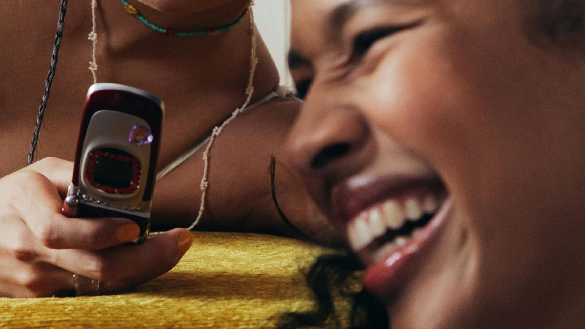 Teenage girls relaxing indoors with a mobile phone, exuding friendship and joy.