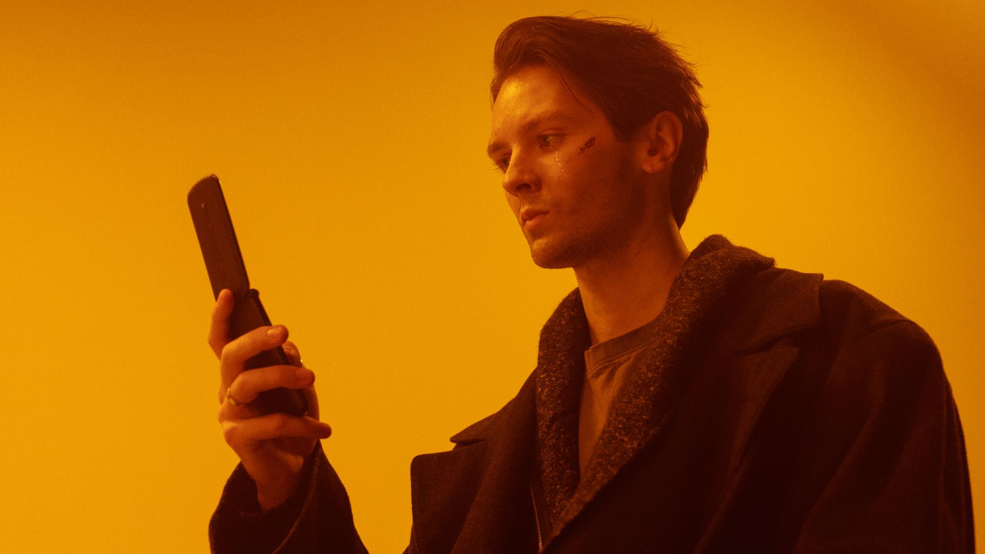 Dramatic studio portrait of a man using a vintage flip phone.