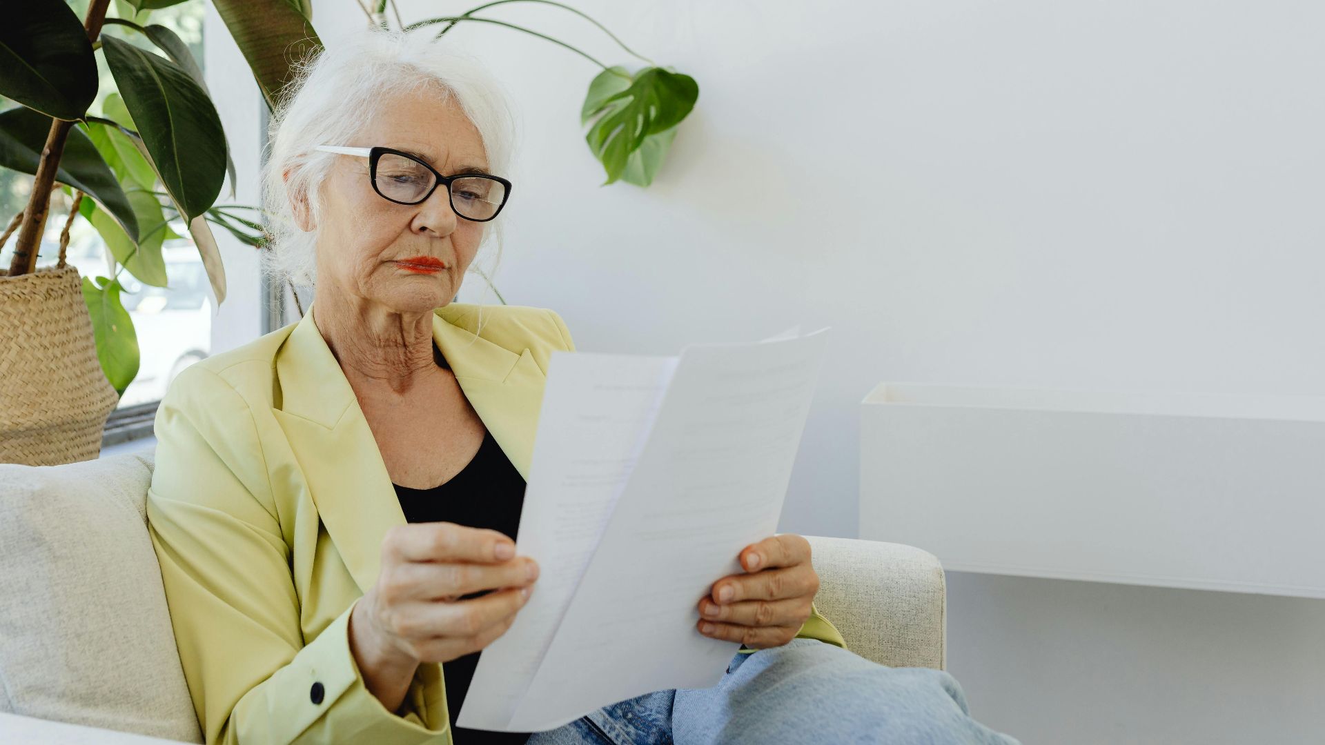 Portrait of a senior businesswoman in a blazer reading documents indoors.