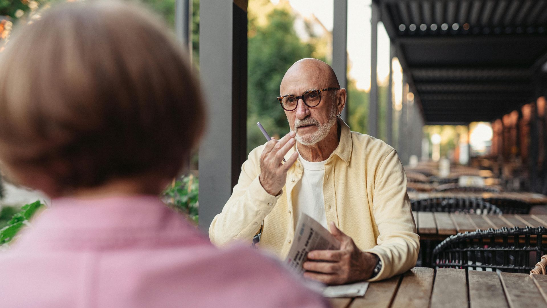 Elderly couple conversing at an outdoor cafe, enjoying a peaceful moment together.