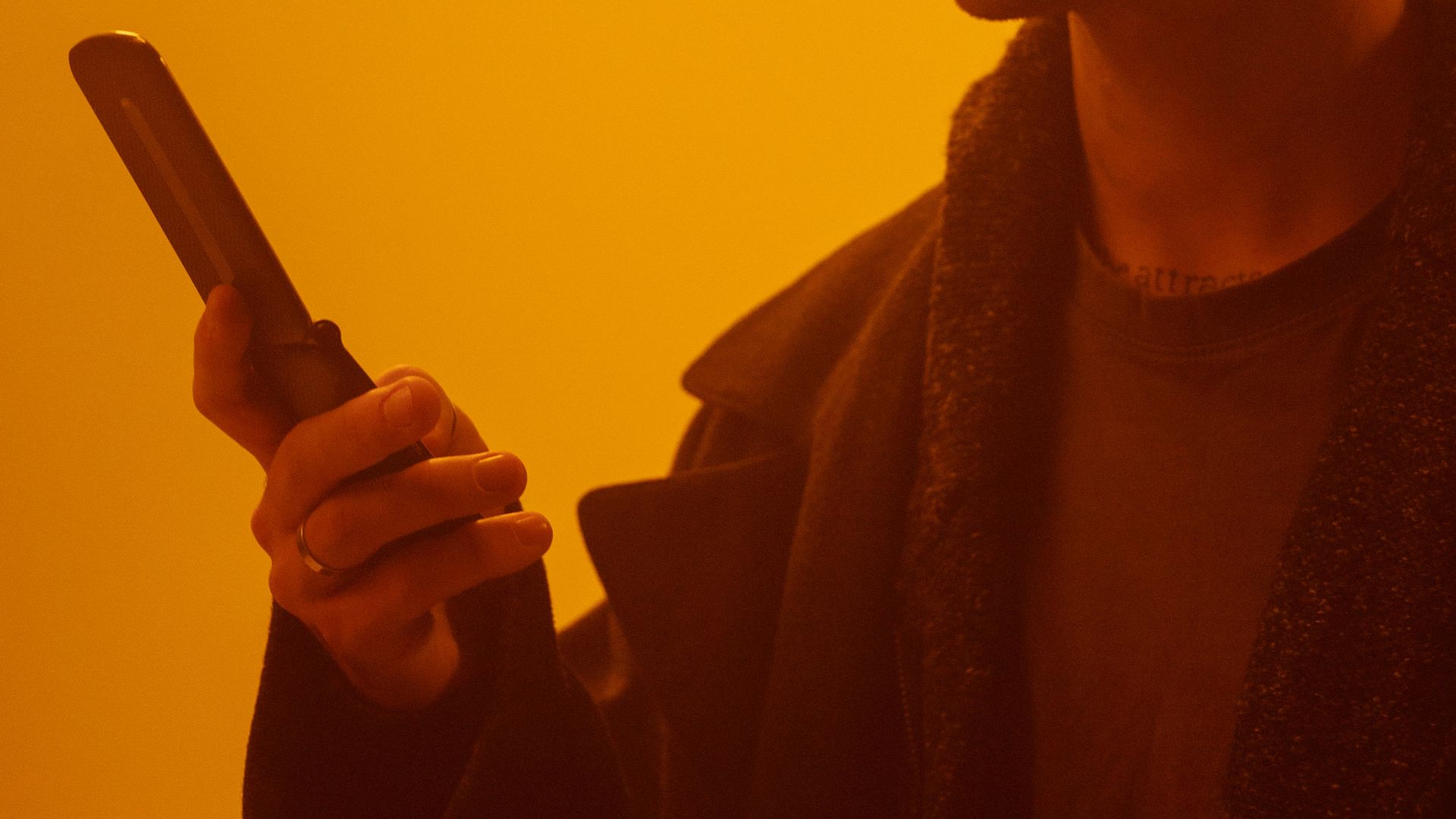 Moody portrait of a man using a flip phone in dystopian lighting.