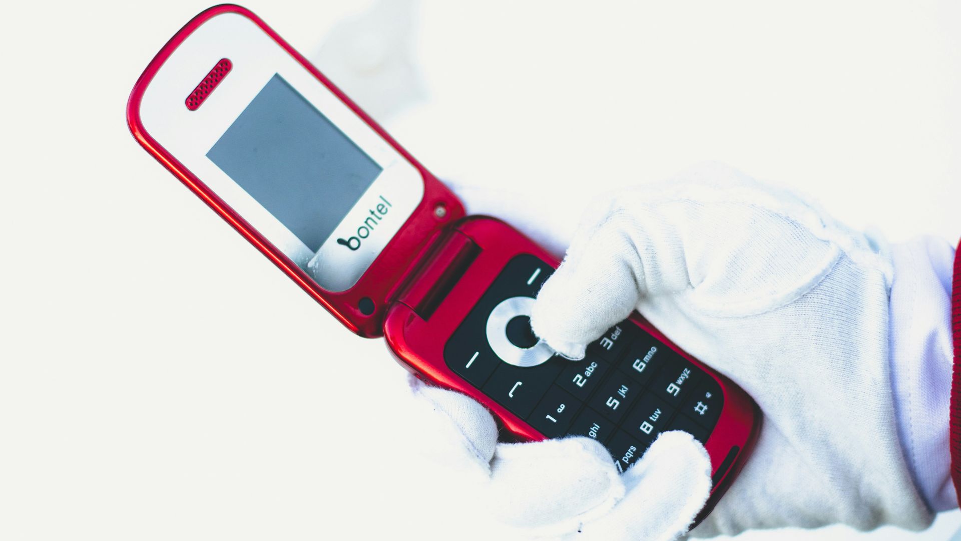 a person in white gloves holding a red cell phone