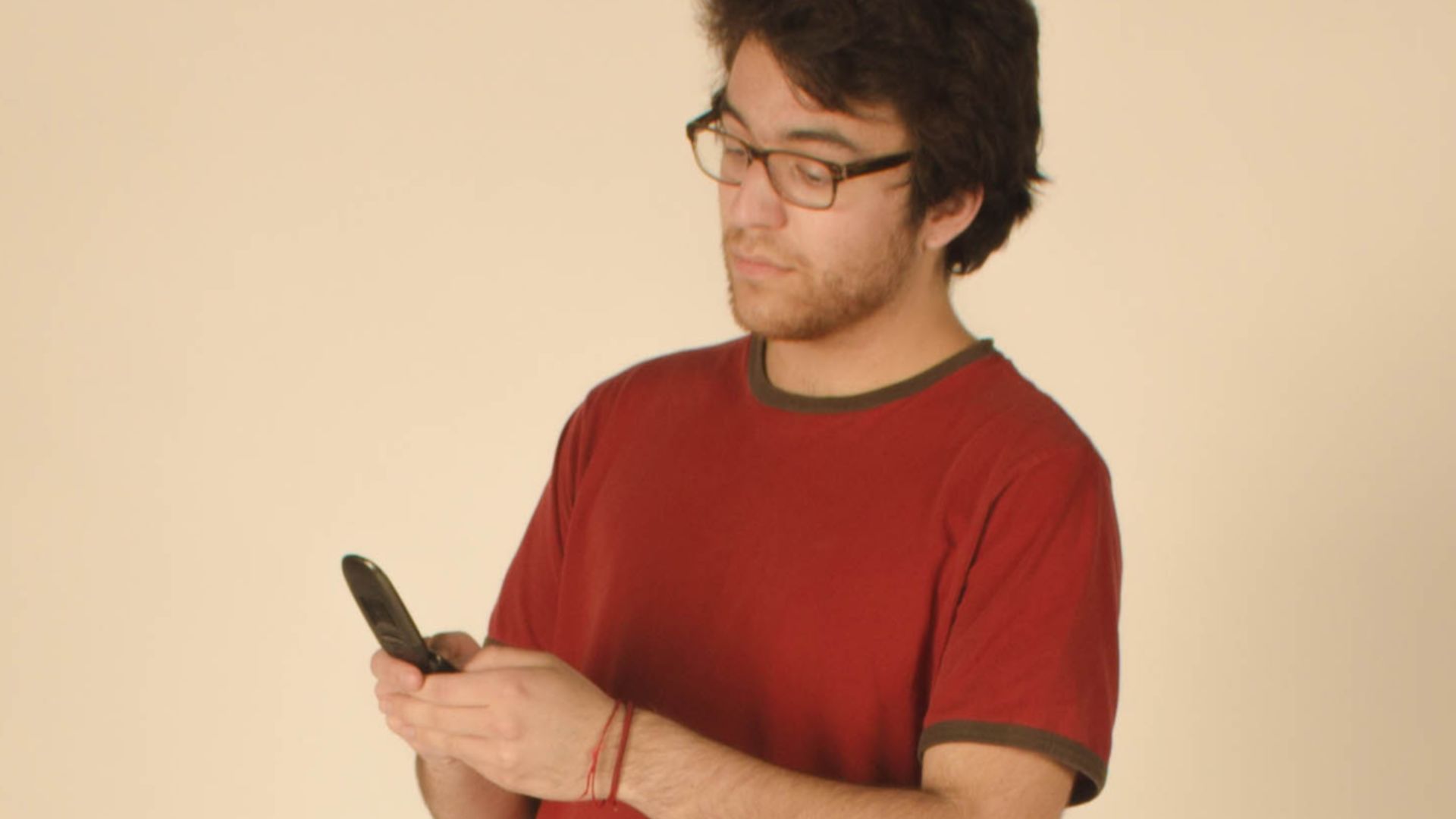 A photograph of a young man using a flip phone