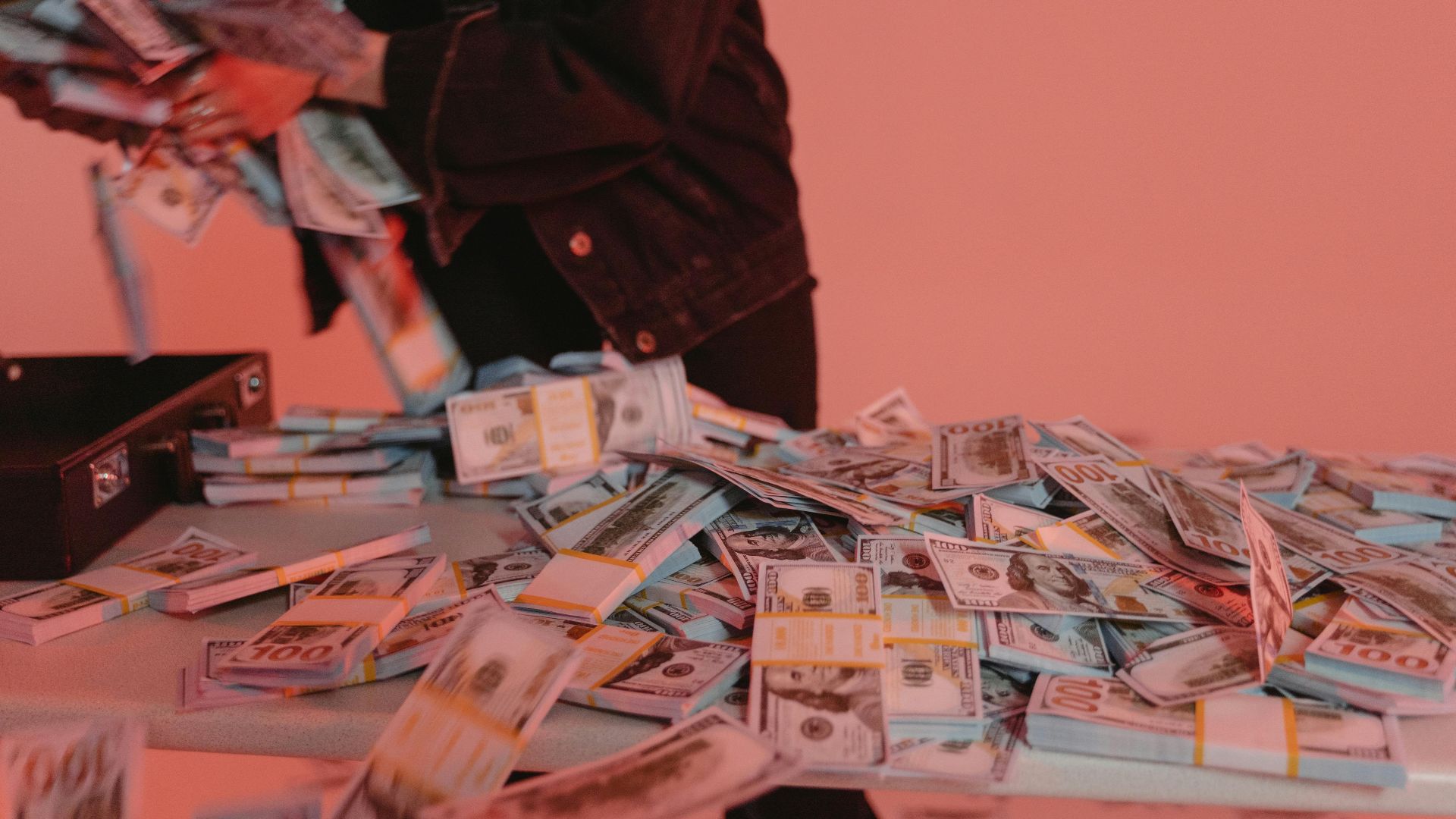 Bundles of US dollar bills on a table with a person organizing them.
