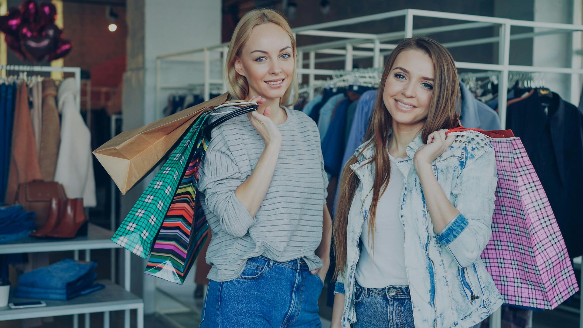 Two young women happily shopping with colorful bags in a boutique, embodying a joyful retail experience.