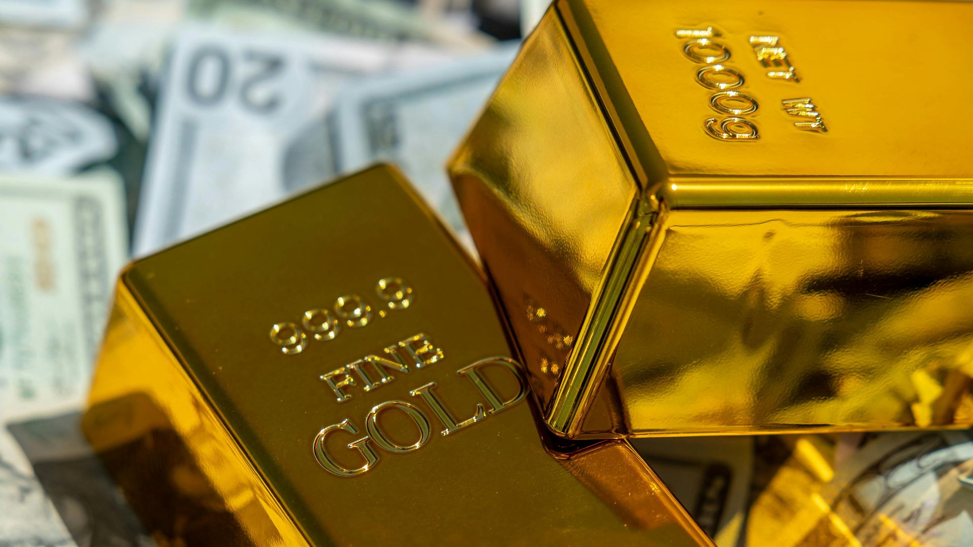 Close-up of gold bars atop US currency, symbolizing wealth and investment.