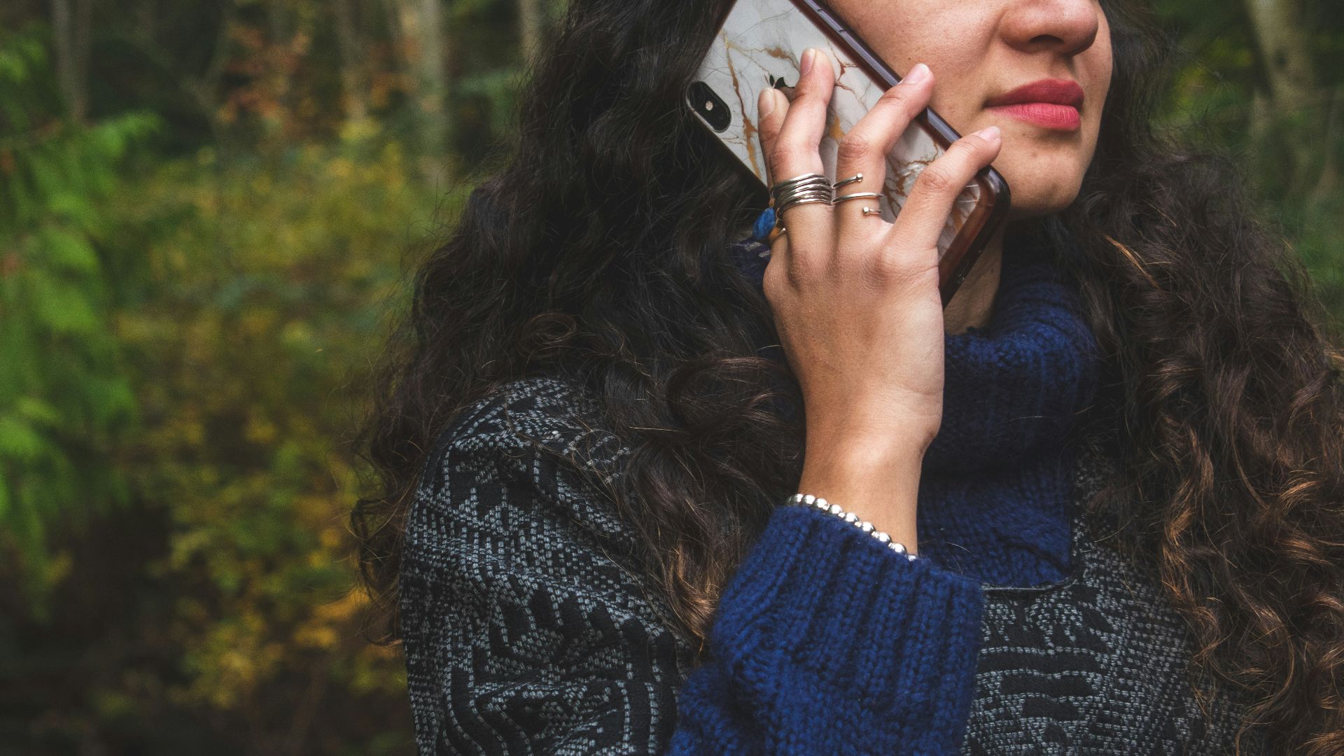woman in blue sweater holding smartphone
