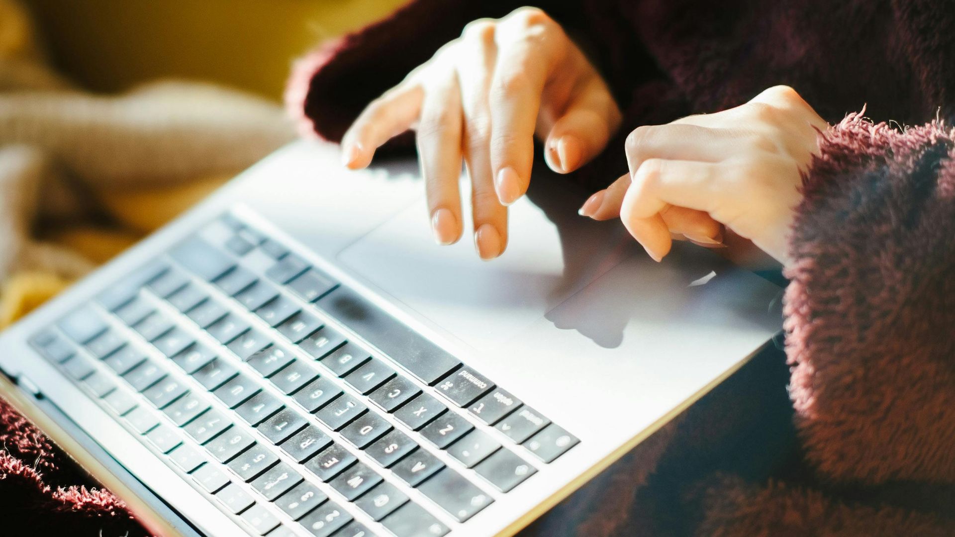 Woman working on a laptop in a cozy environment, wearing a bathrobe.