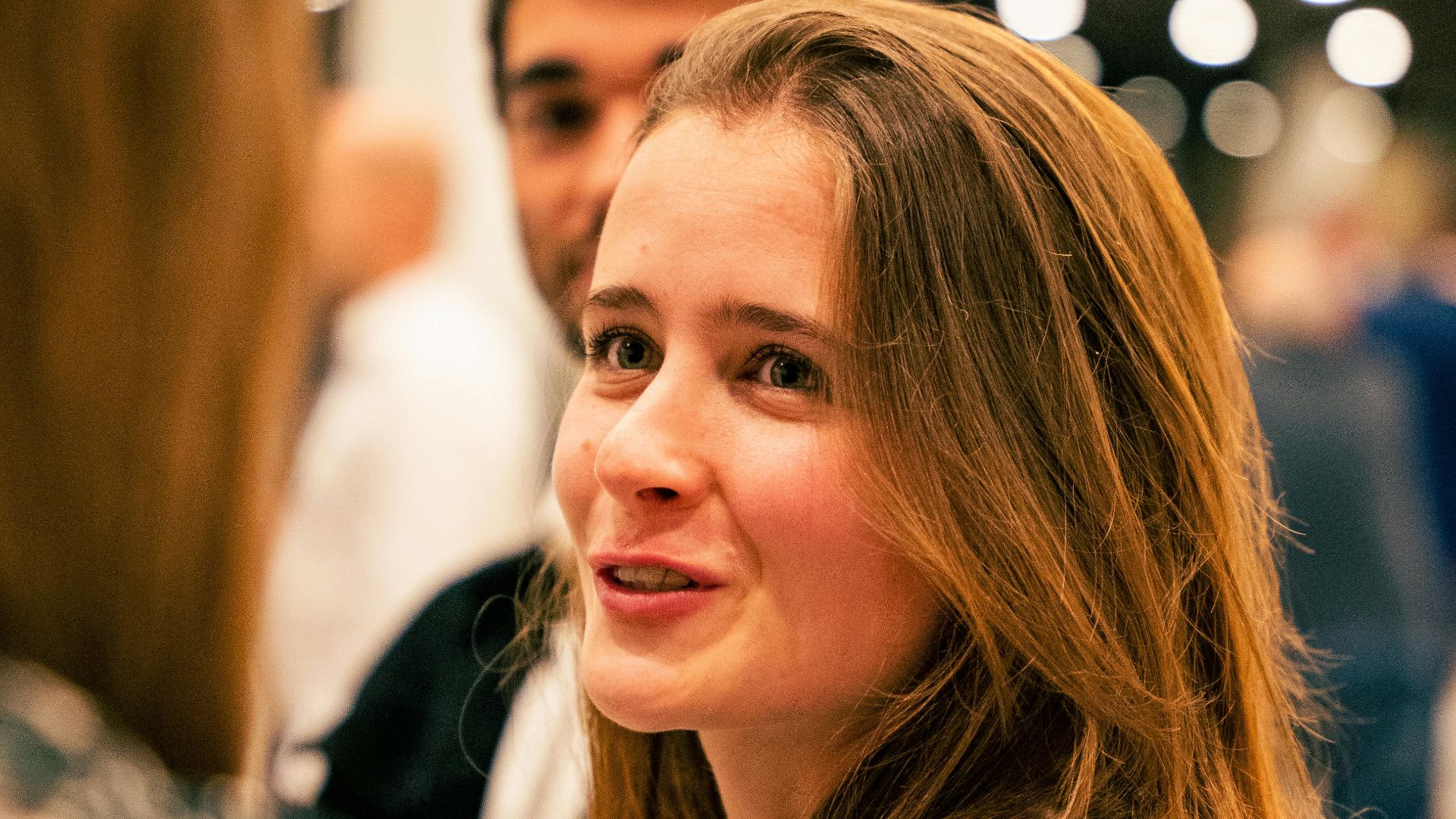 Young woman in stylish animal print blouse interacts with friends at a lively social gathering.