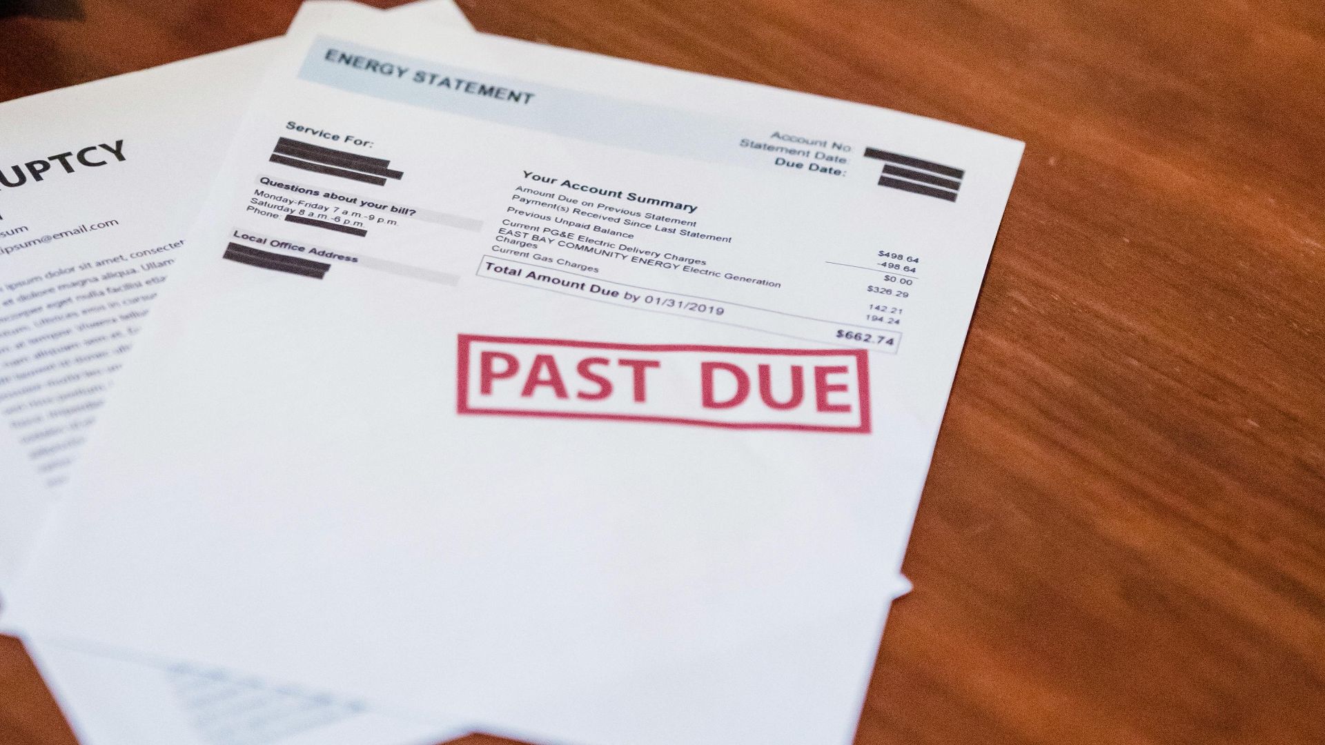 Close-up of past due financial documents on a wooden table, suggesting economic hardship.