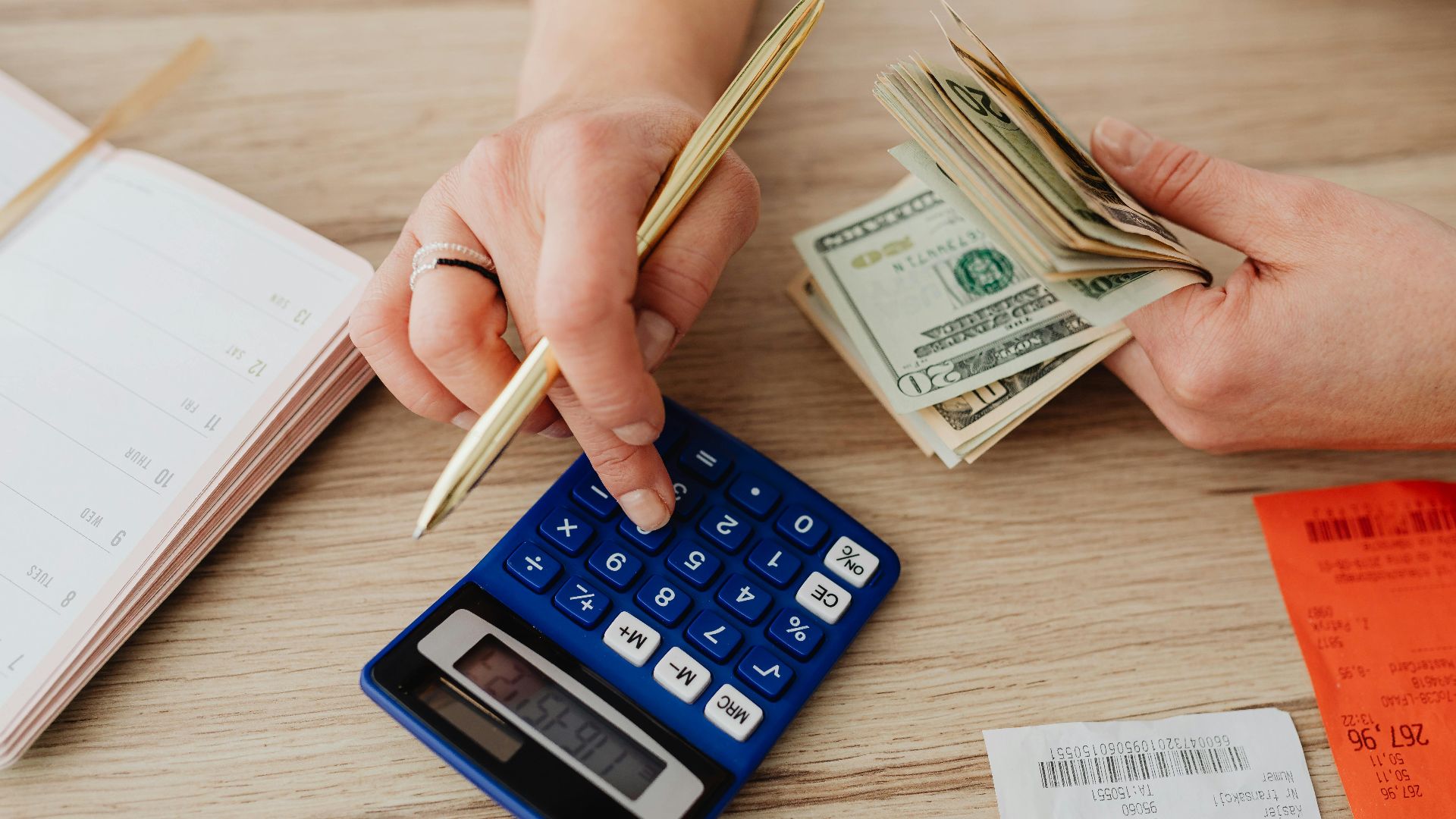 Hands handling cash and calculator for budget planning. Modern financial scene.