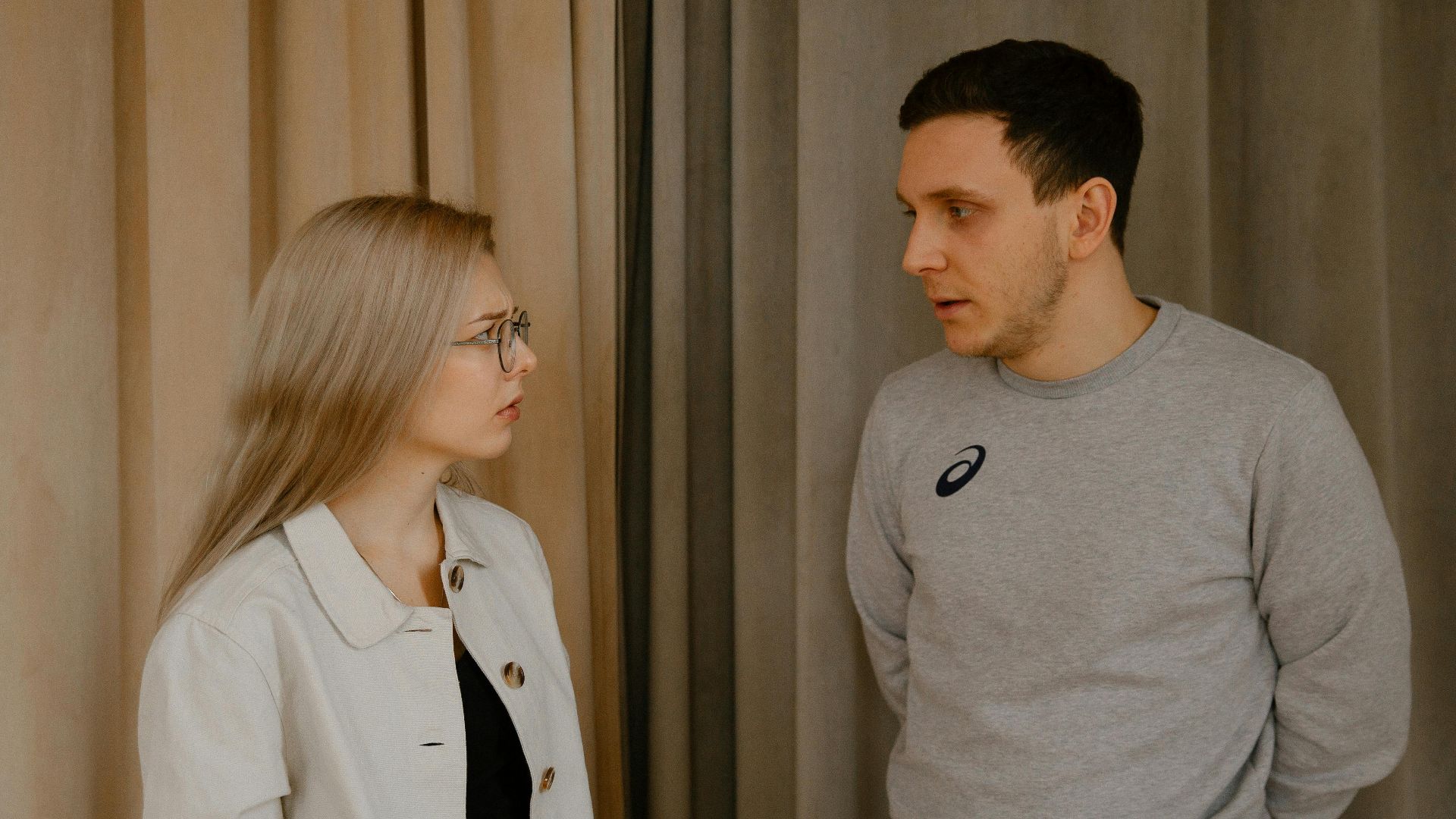 Man and woman having a serious conversation indoors, focused expressions.