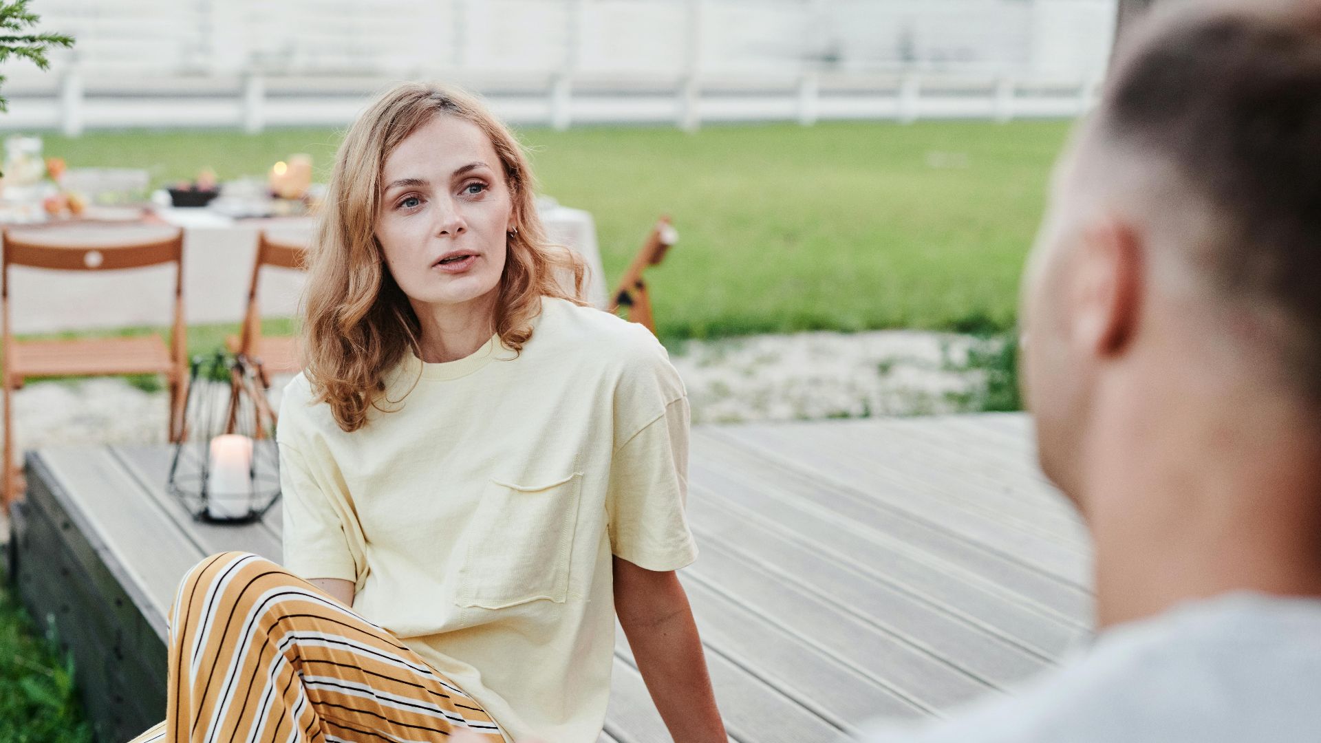 A couple engaged in a thoughtful conversation outdoors in a relaxed garden setting.