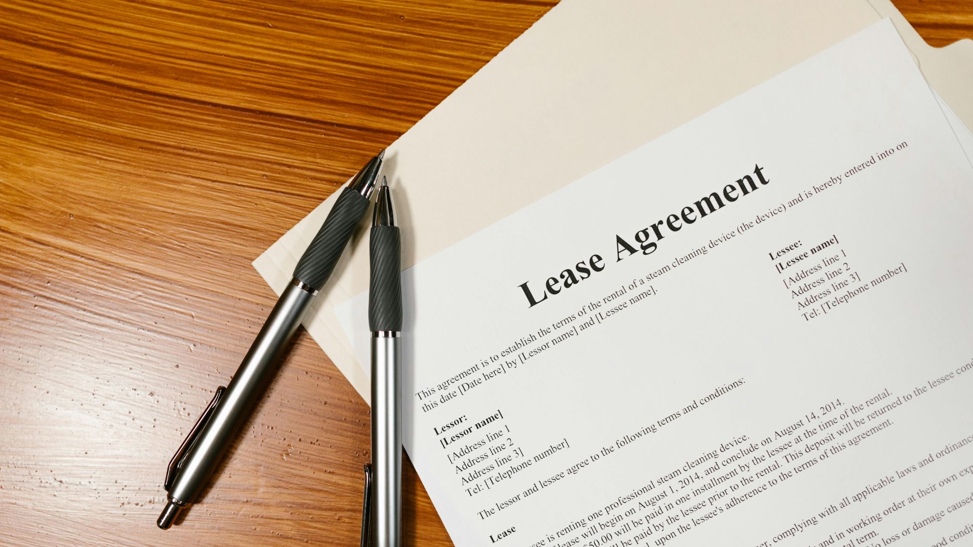 High-angle view of a lease agreement and pens on a wooden desk.
