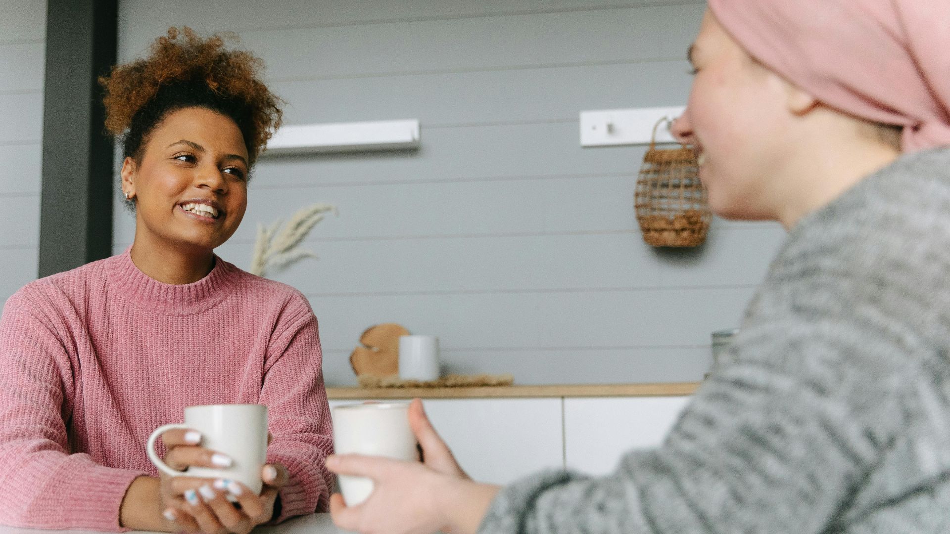 Two women share a joyful coffee moment at home, embodying friendship and warmth.
