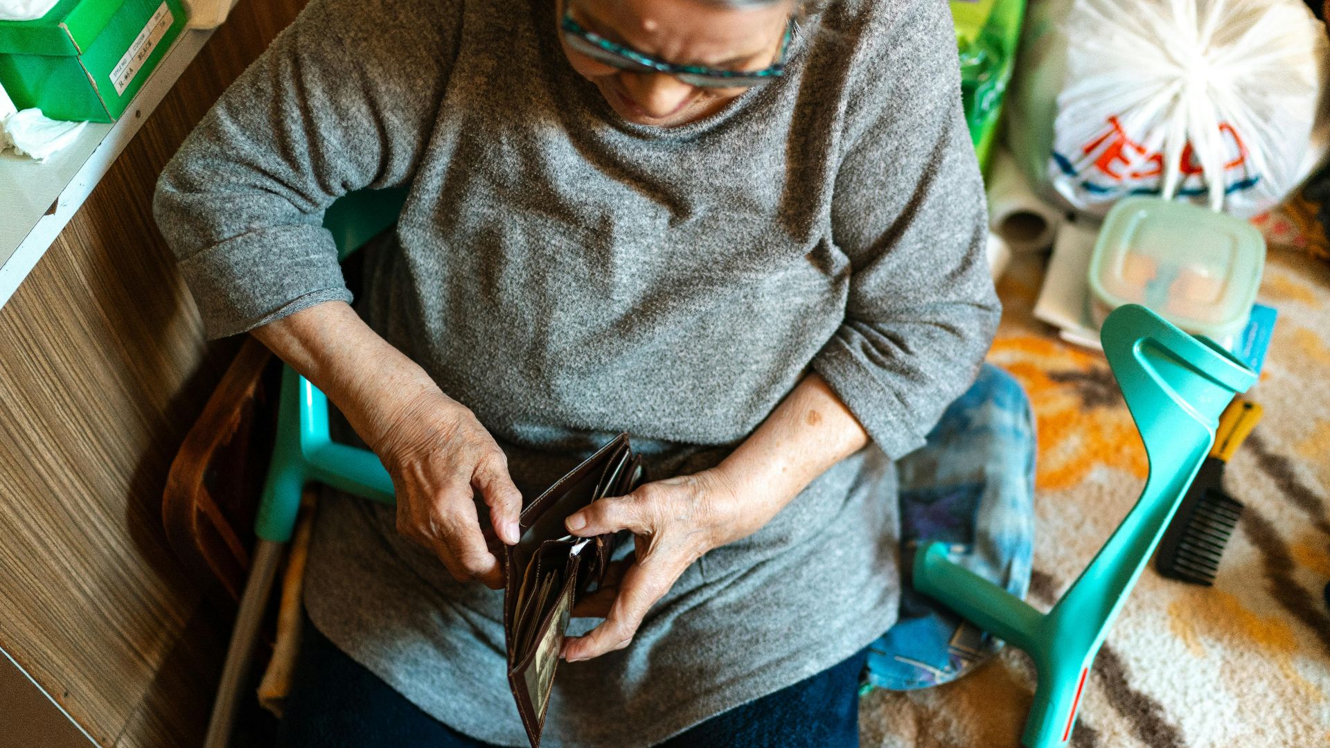 Elderly woman sitting indoors managing her wallet. Home care theme.