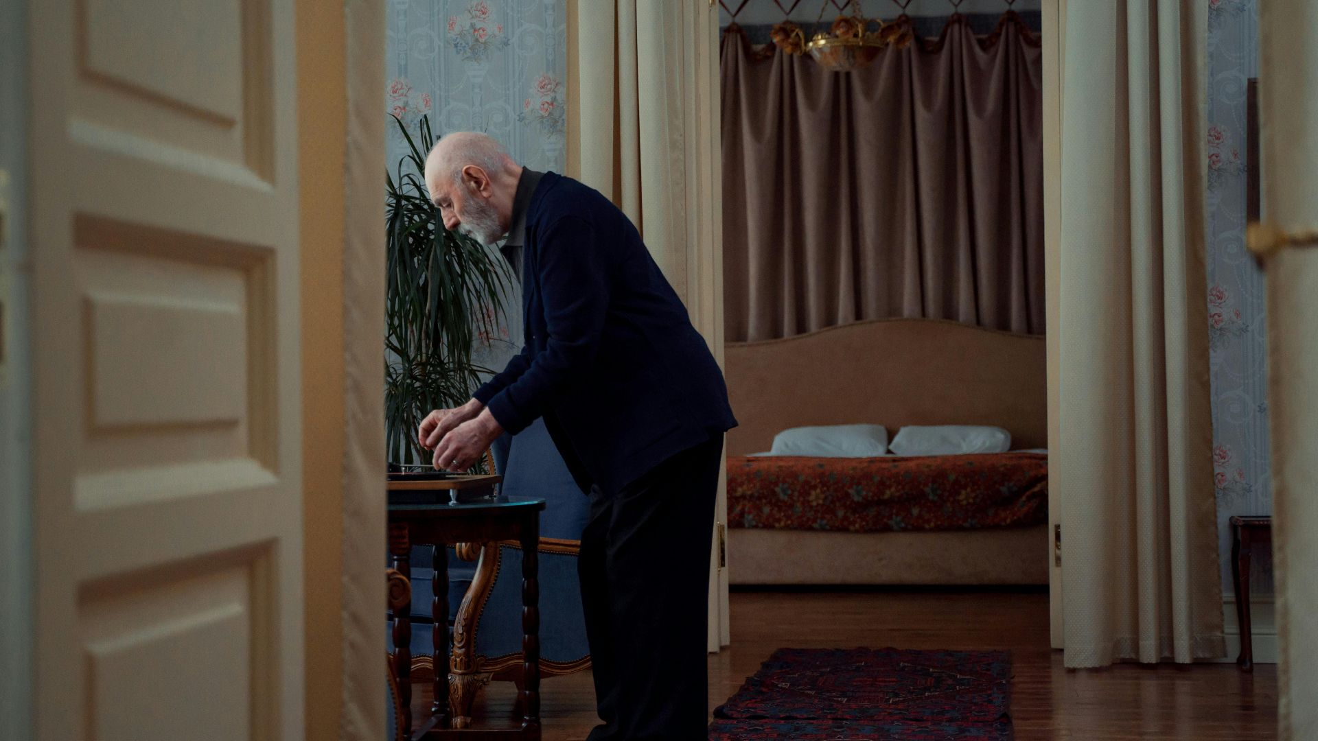 Senior man enjoying music on a turntable in a cozy, vintage home setting. Warm interior design.