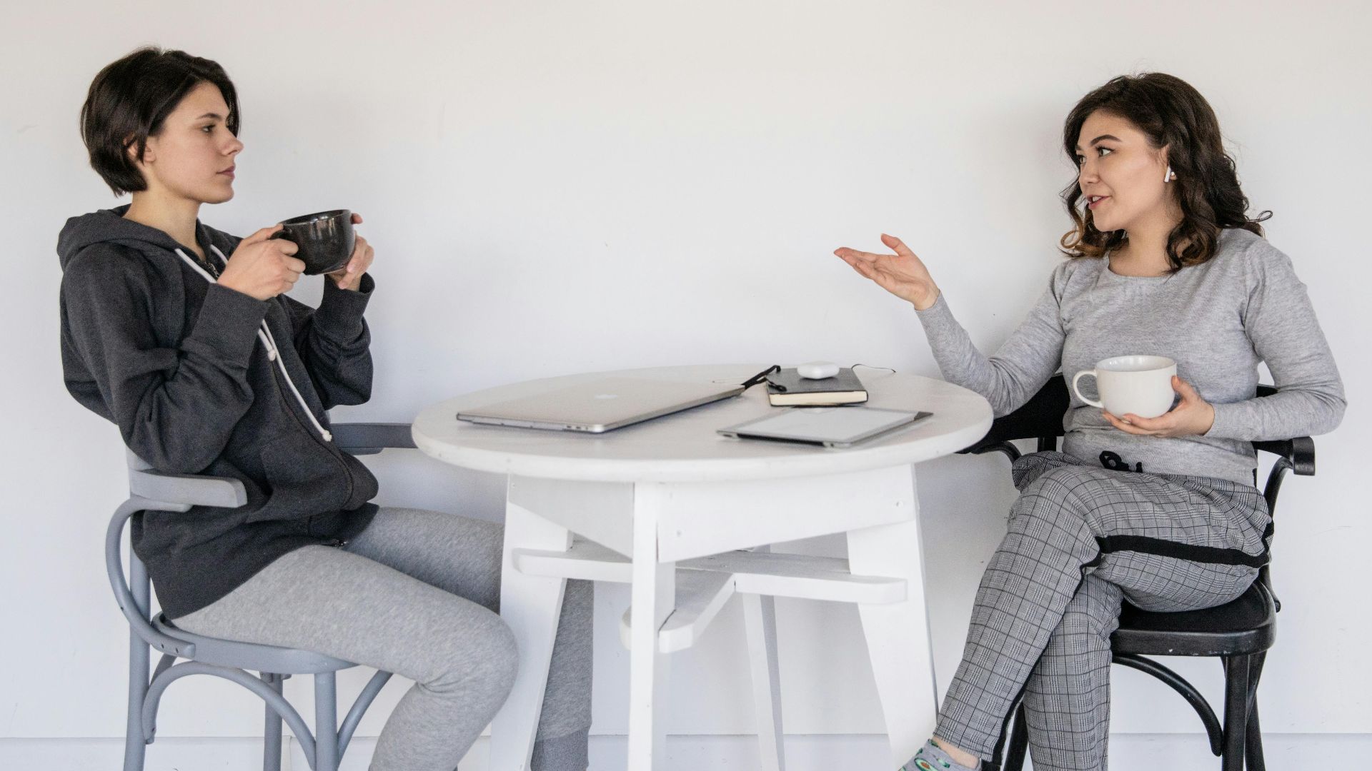 Two women enjoying a casual conversation with coffee in a cozy indoor setting, enhancing connections.