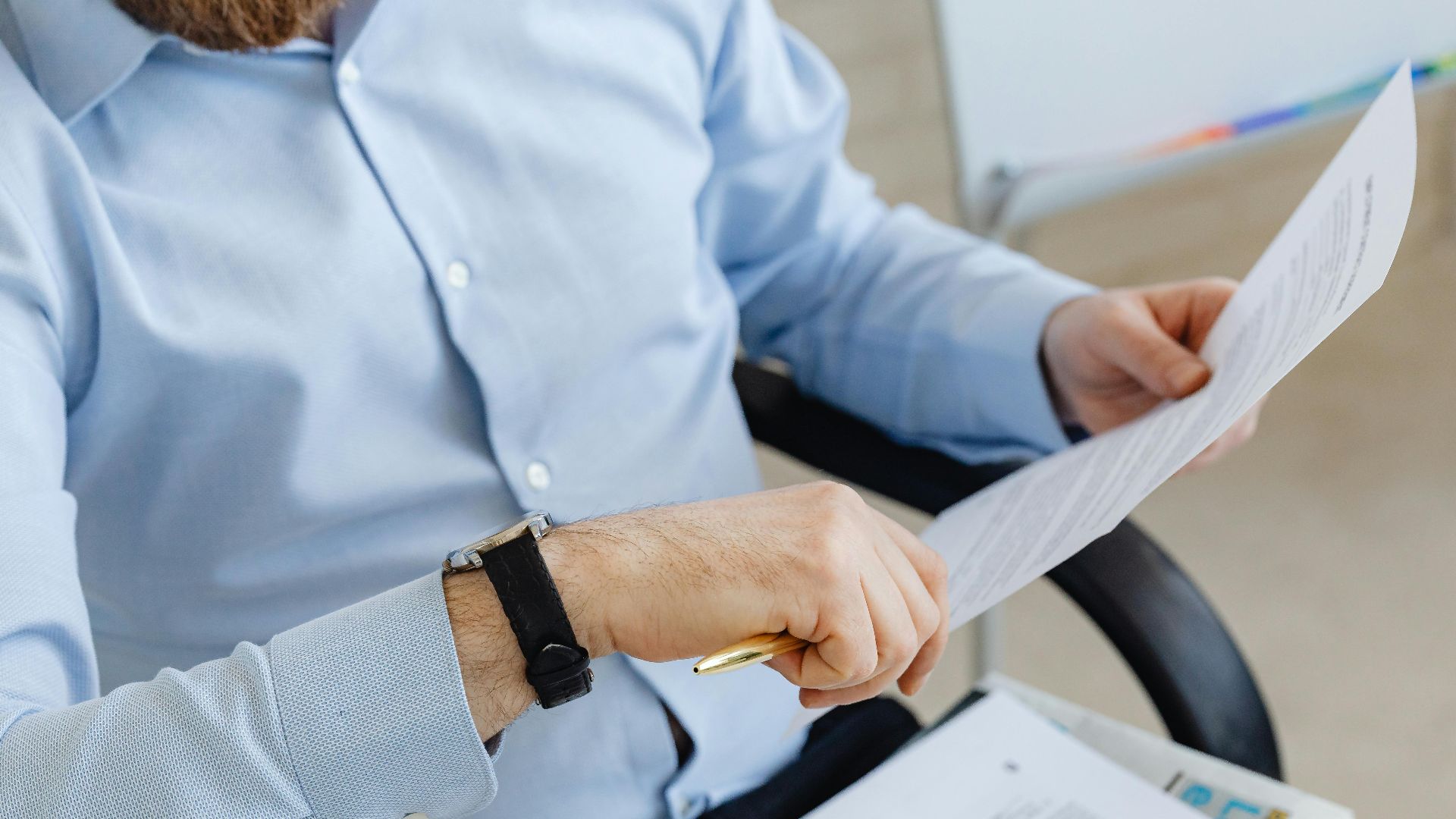 Businessman reviewing papers in office setting, highlighting analysis and attention to detail.