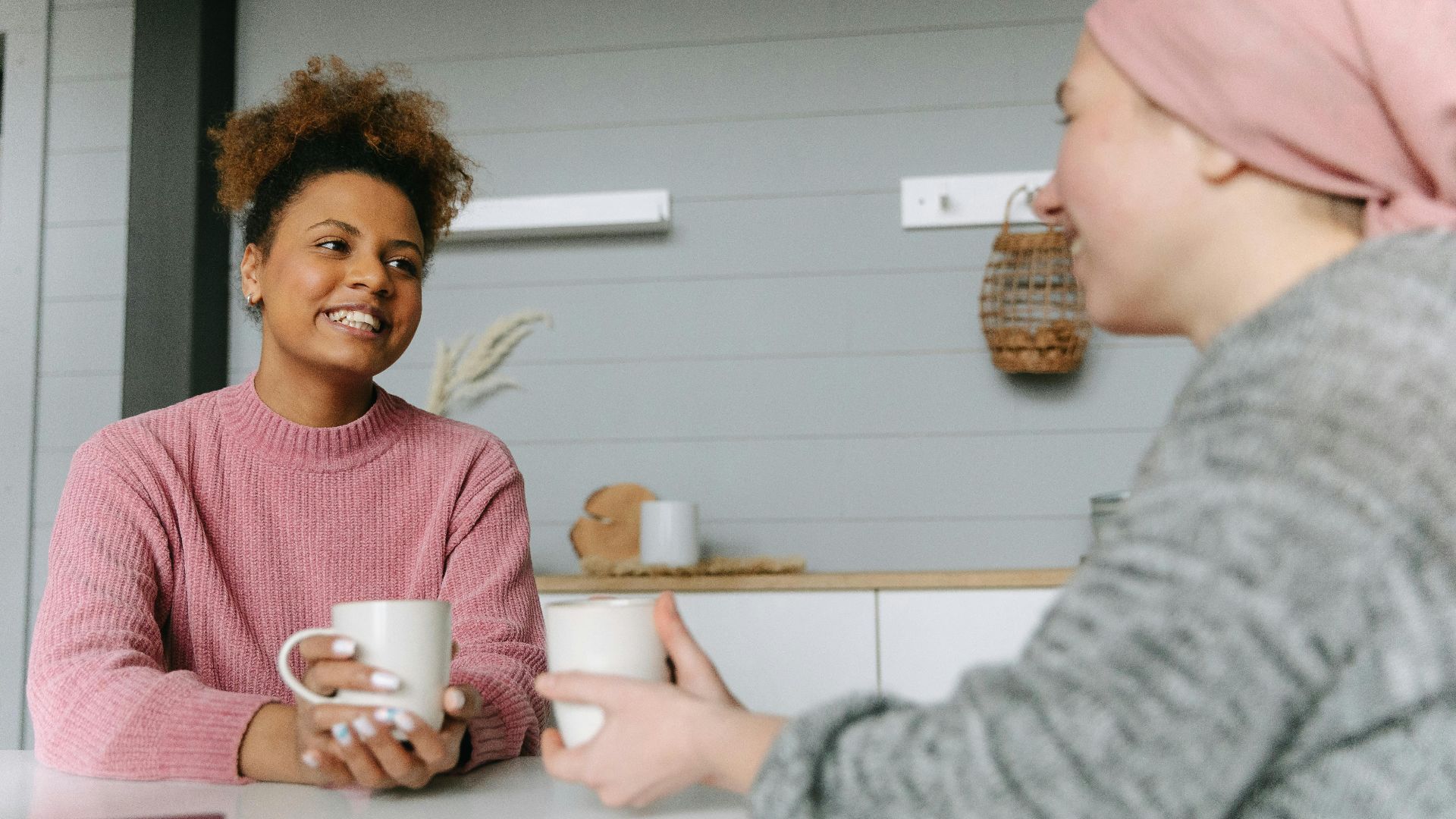 Two women share a joyful coffee moment at home, embodying friendship and warmth.