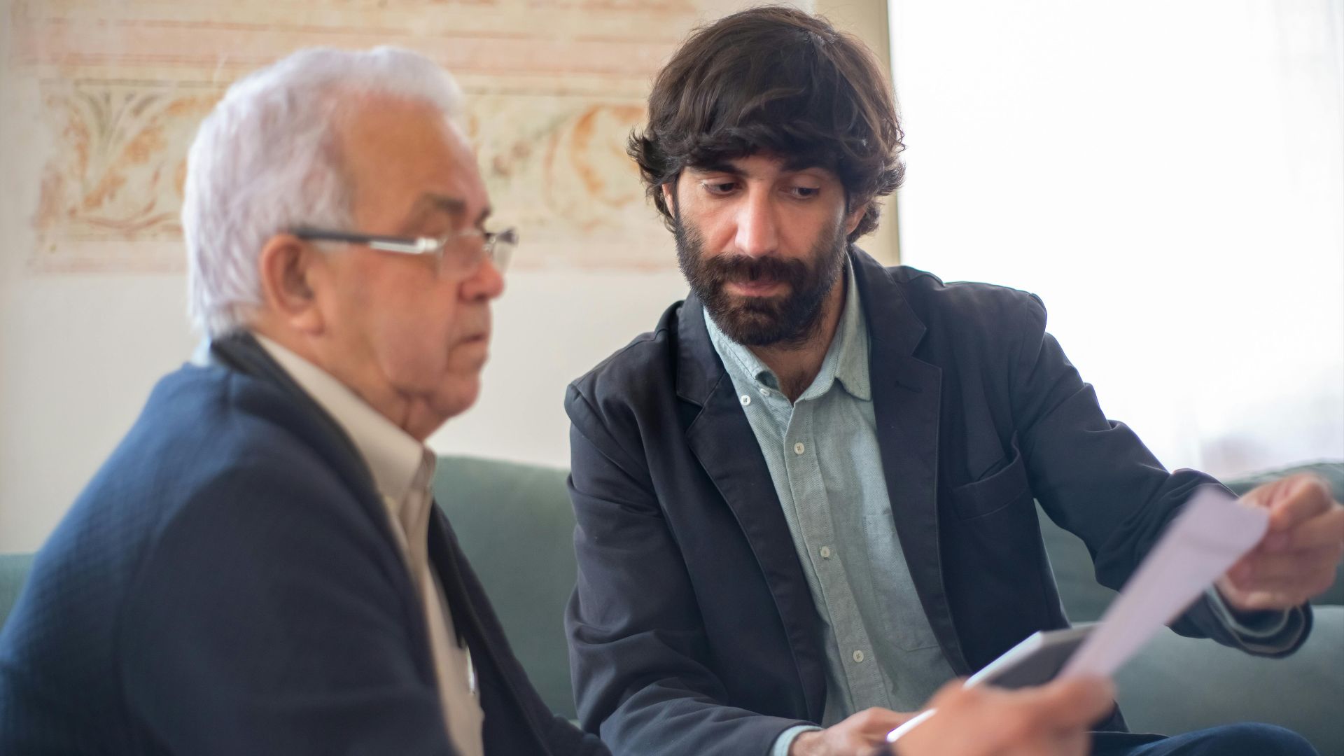 Two men engaged in a business consultation, reviewing documents in a professional setting.