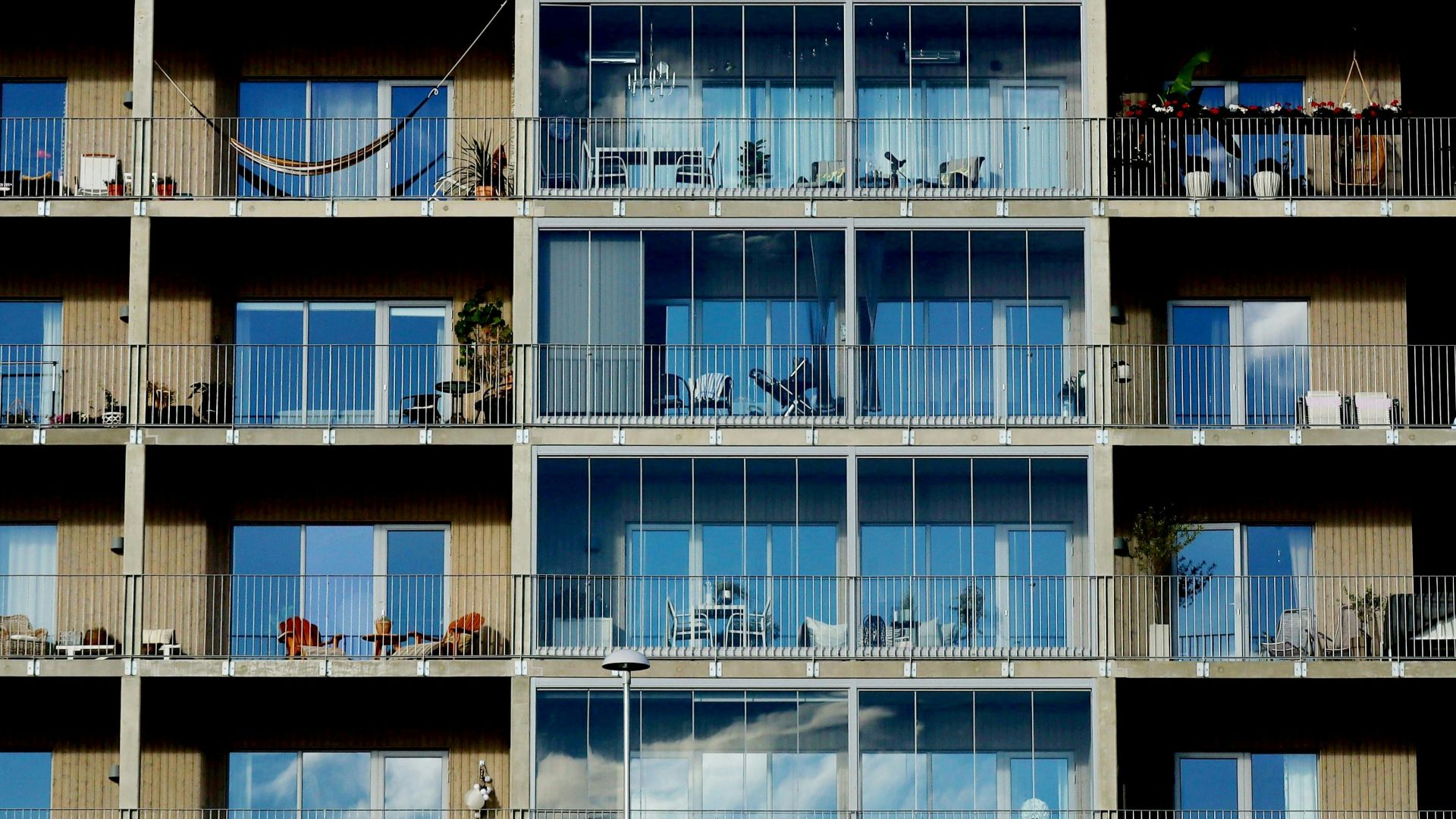 Facade of a modern residential building featuring glass windows, balconies, and metal railings.