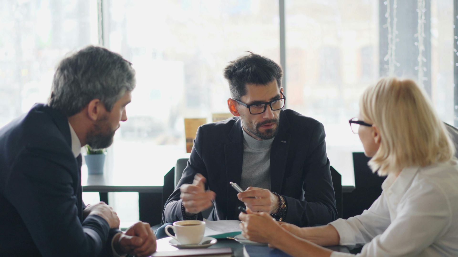 Business professionals engaged in a meeting at a café, sharing ideas and discussion.