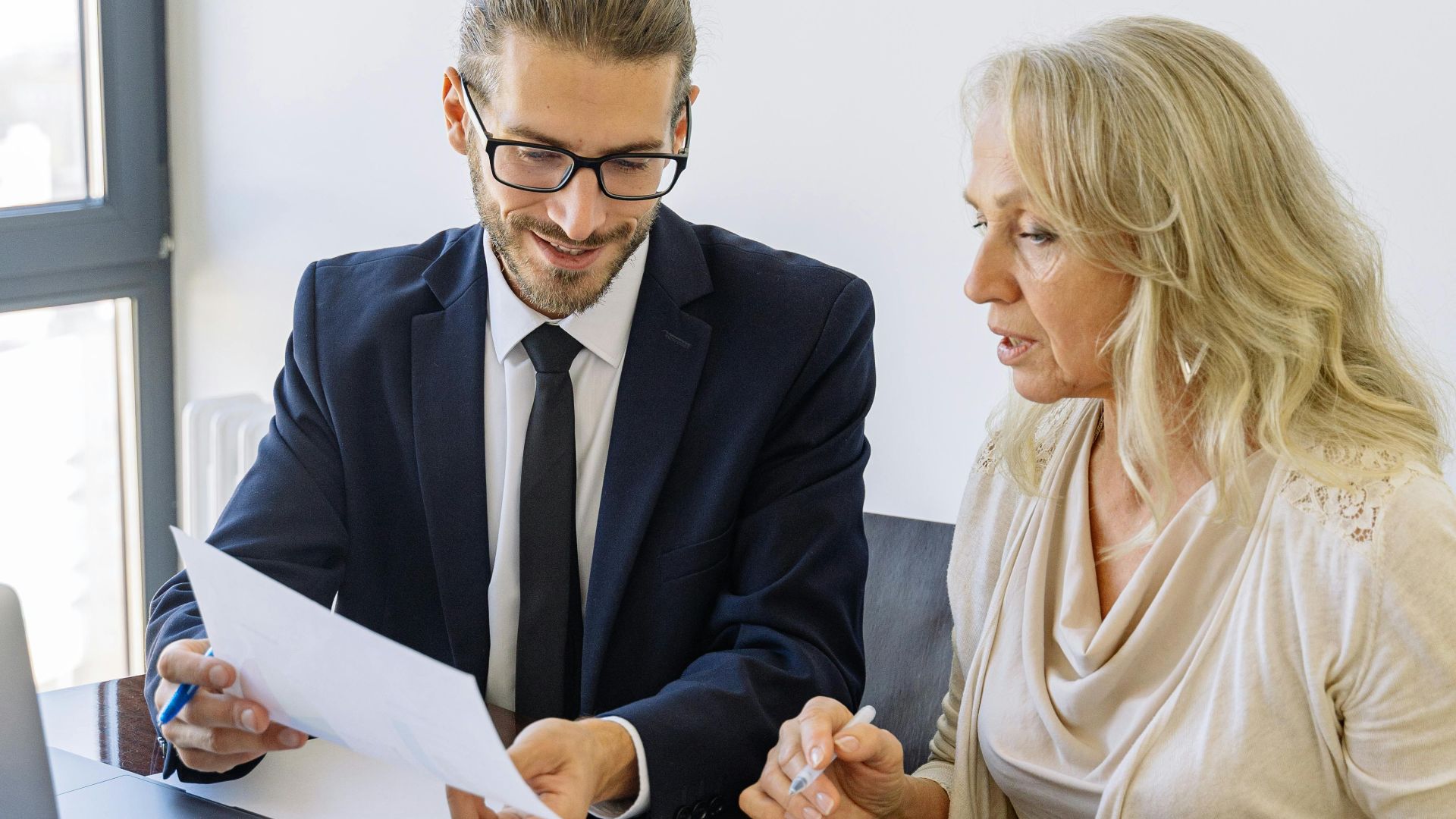 Two business professionals reviewing financial documents and graphs during a meeting.