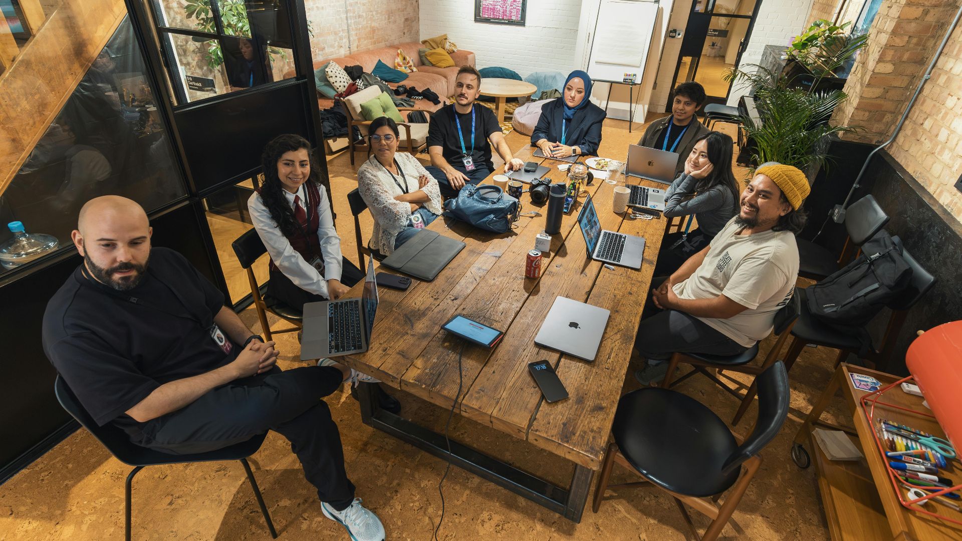A group of diverse professionals collaborating in a modern office setting with laptops and technology.