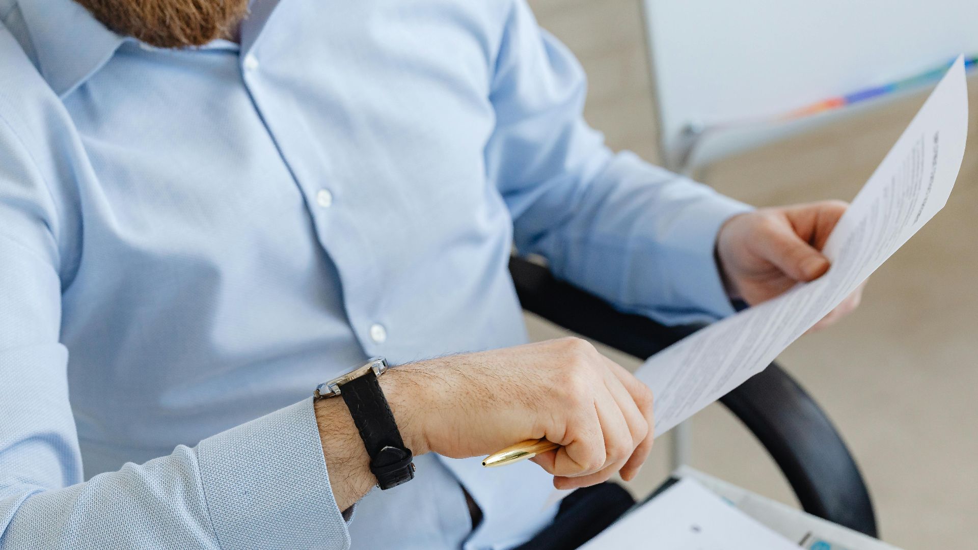 Businessman reviewing papers in office setting, highlighting analysis and attention to detail.