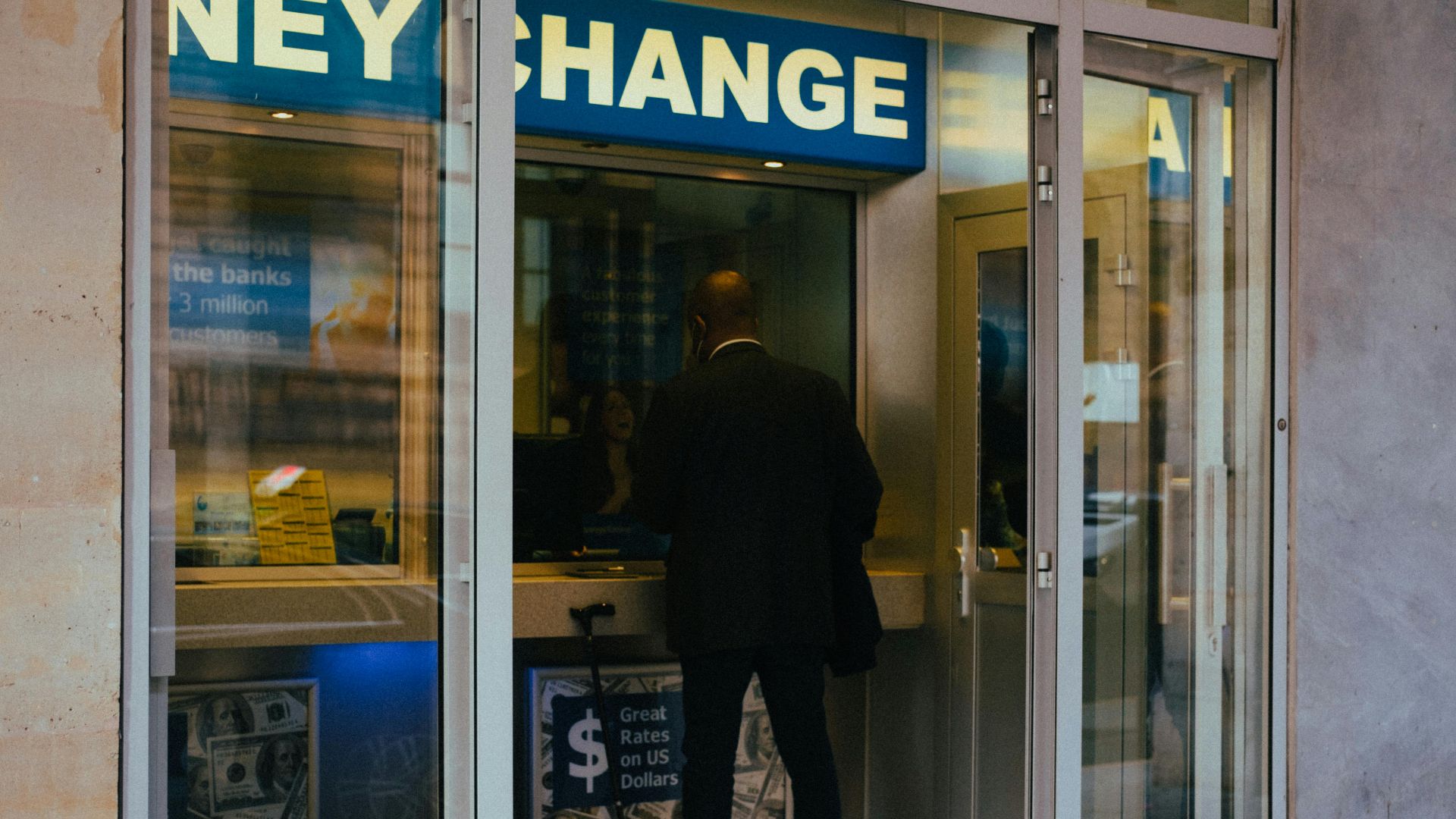 A businessman changes money at a currency exchange counter indoors.